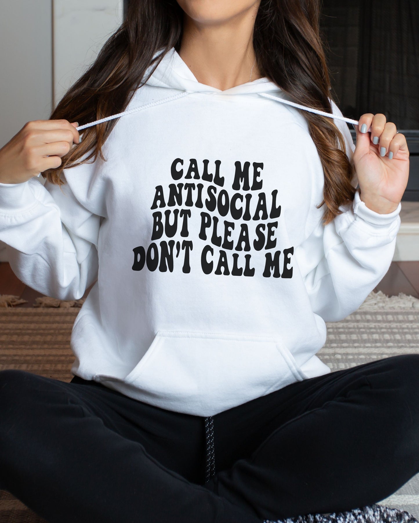 Person wearing a white hoodie with text on it, sitting on a couch.