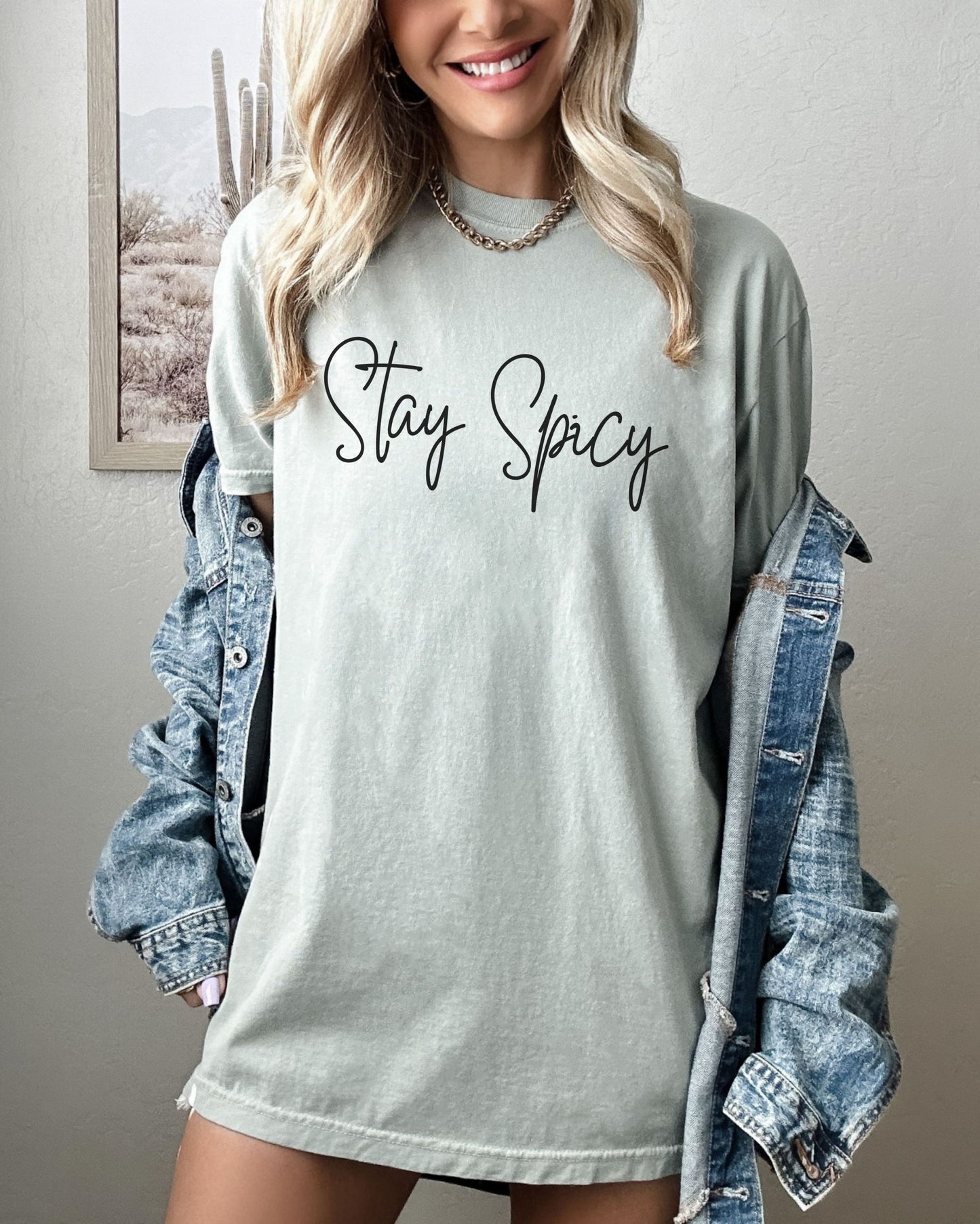 Person wearing a light gray t-shirt with 'Stay Spicy' text, paired with a denim jacket.