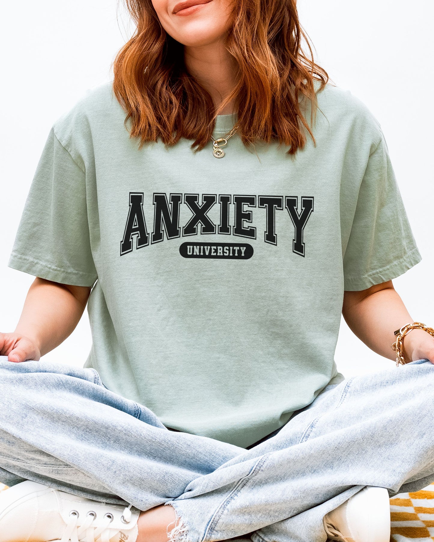 Person wearing a light green t-shirt with 'ANXIETY UNIVERSITY' text.