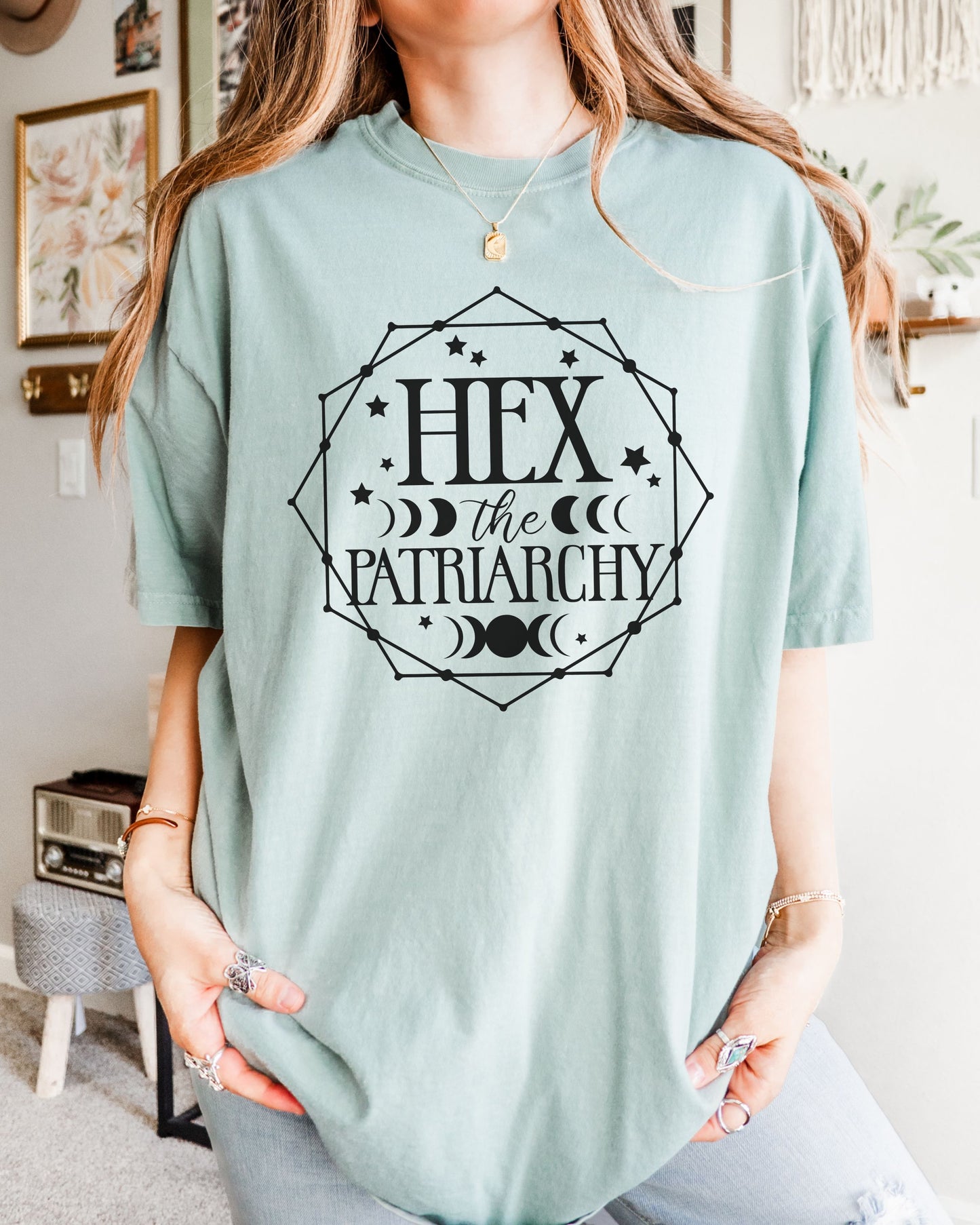 Person wearing a light blue t-shirt with 'Hex the Patriarchy' text in a decorative frame.