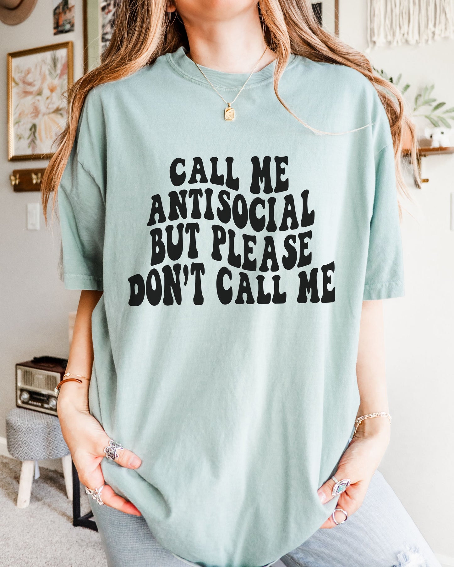 Person wearing a light blue t-shirt with text in a room.