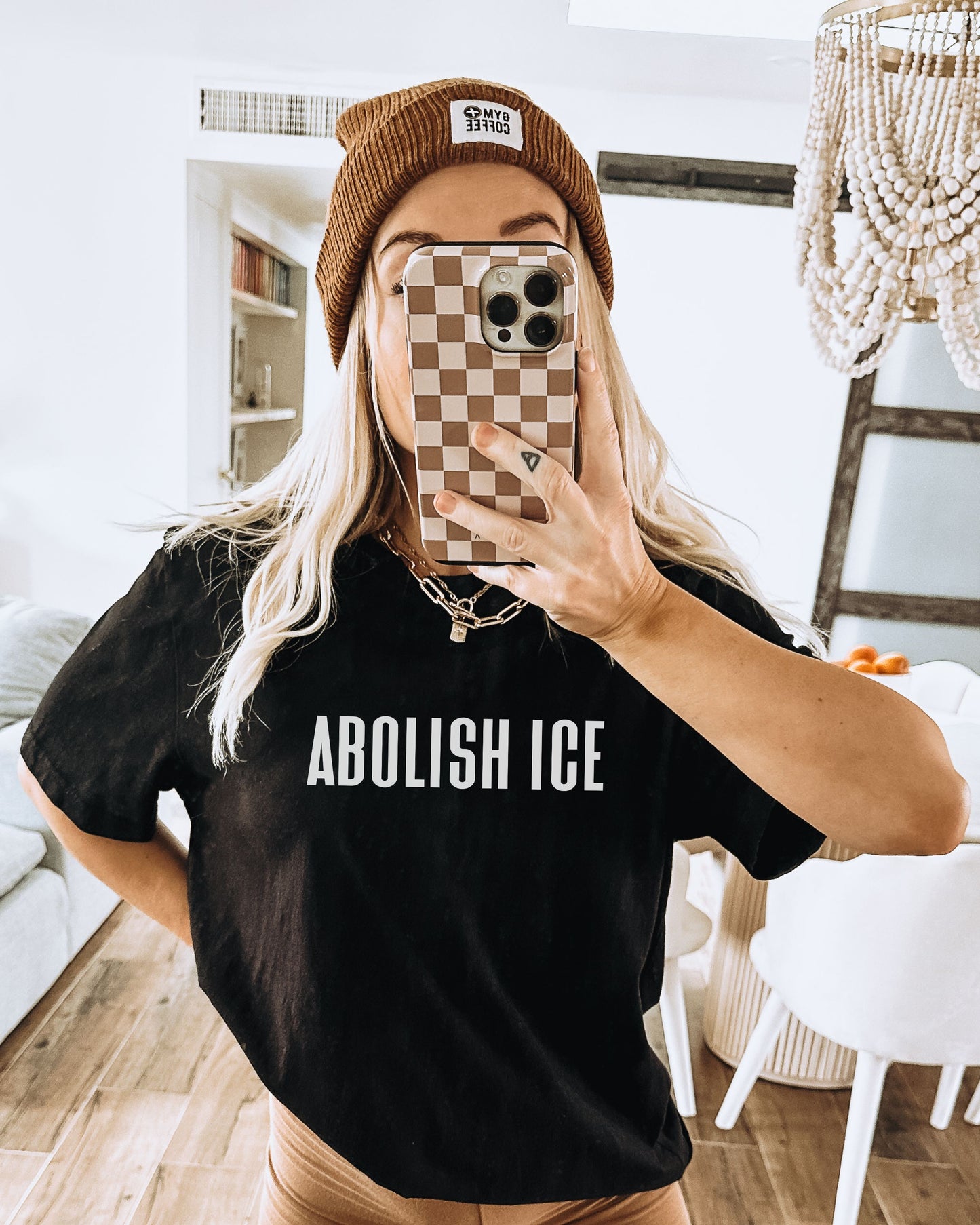 Person wearing a black t-shirt with 'ABOLISH ICE' text, taking a mirror selfie.