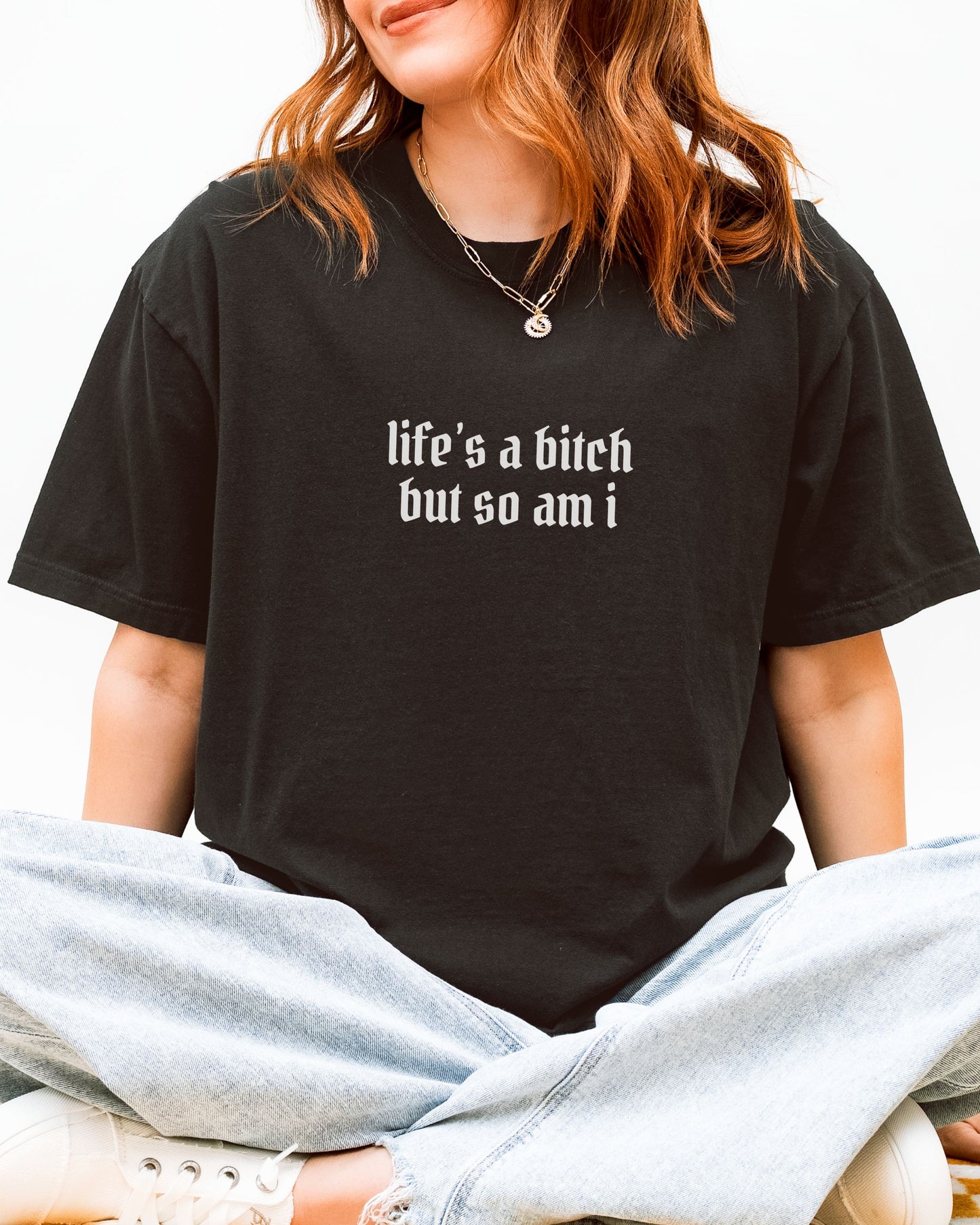 Person wearing a black t-shirt with text, sitting on a white background