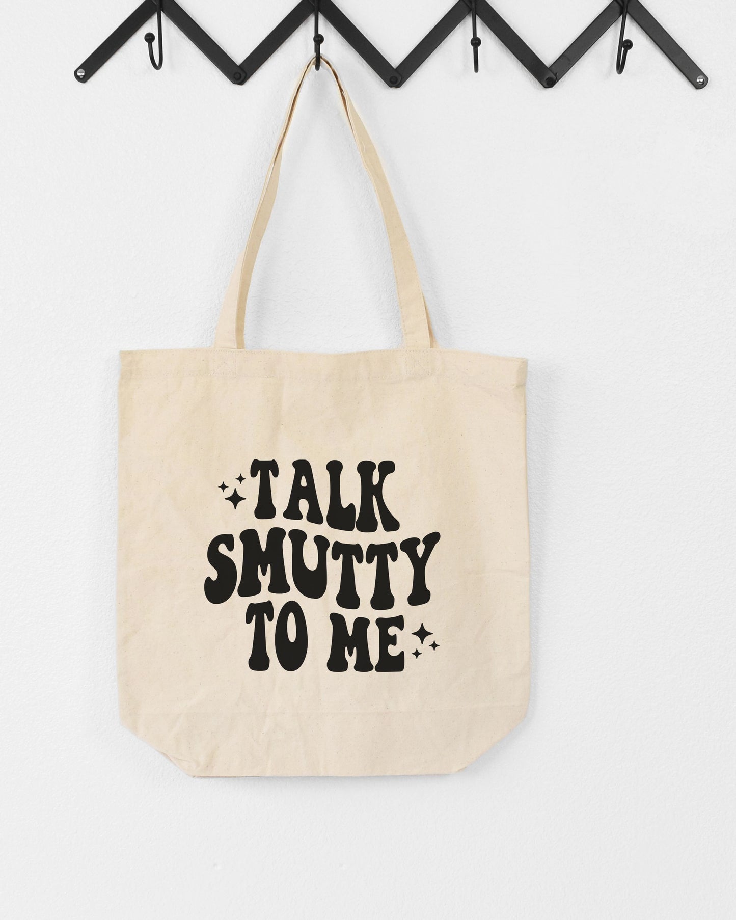 Beige tote bag with 'Talk Smutty To Me' text on a white background