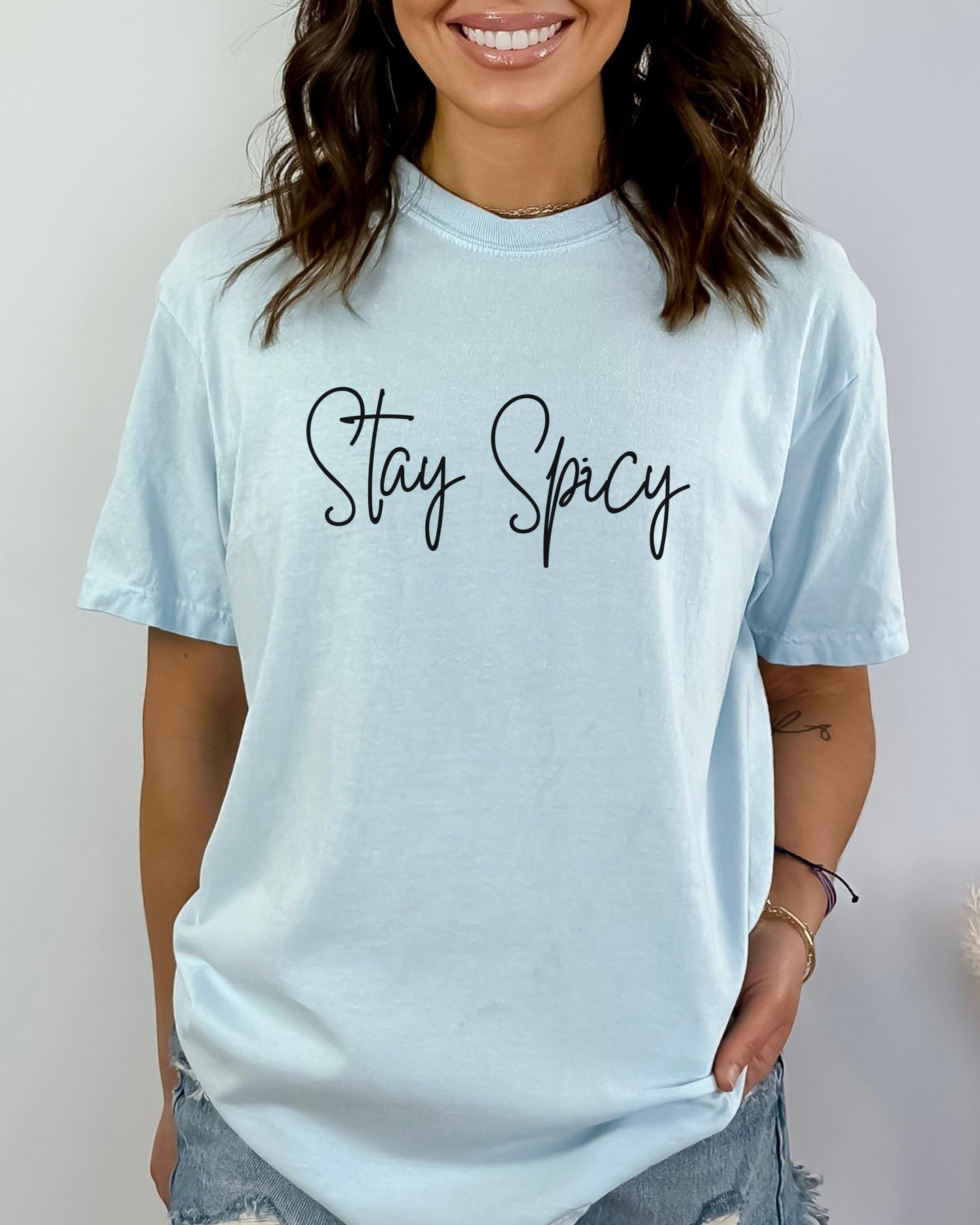 Woman wearing a light blue t-shirt with 'Stay Spicy' text on a plain background