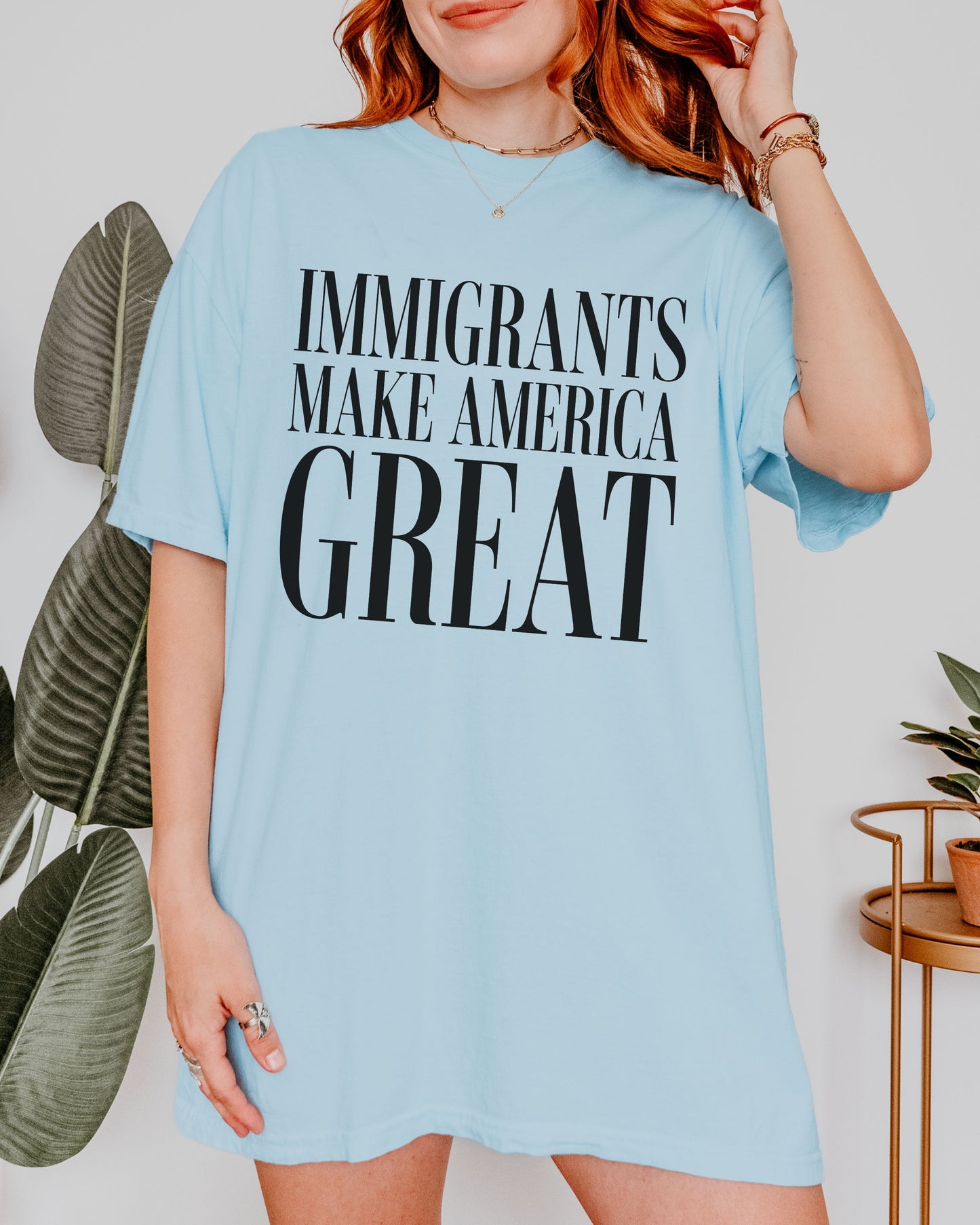 Person wearing a light blue t-shirt with 'IMMIGRANTS MAKE AMERICA GREAT' text.