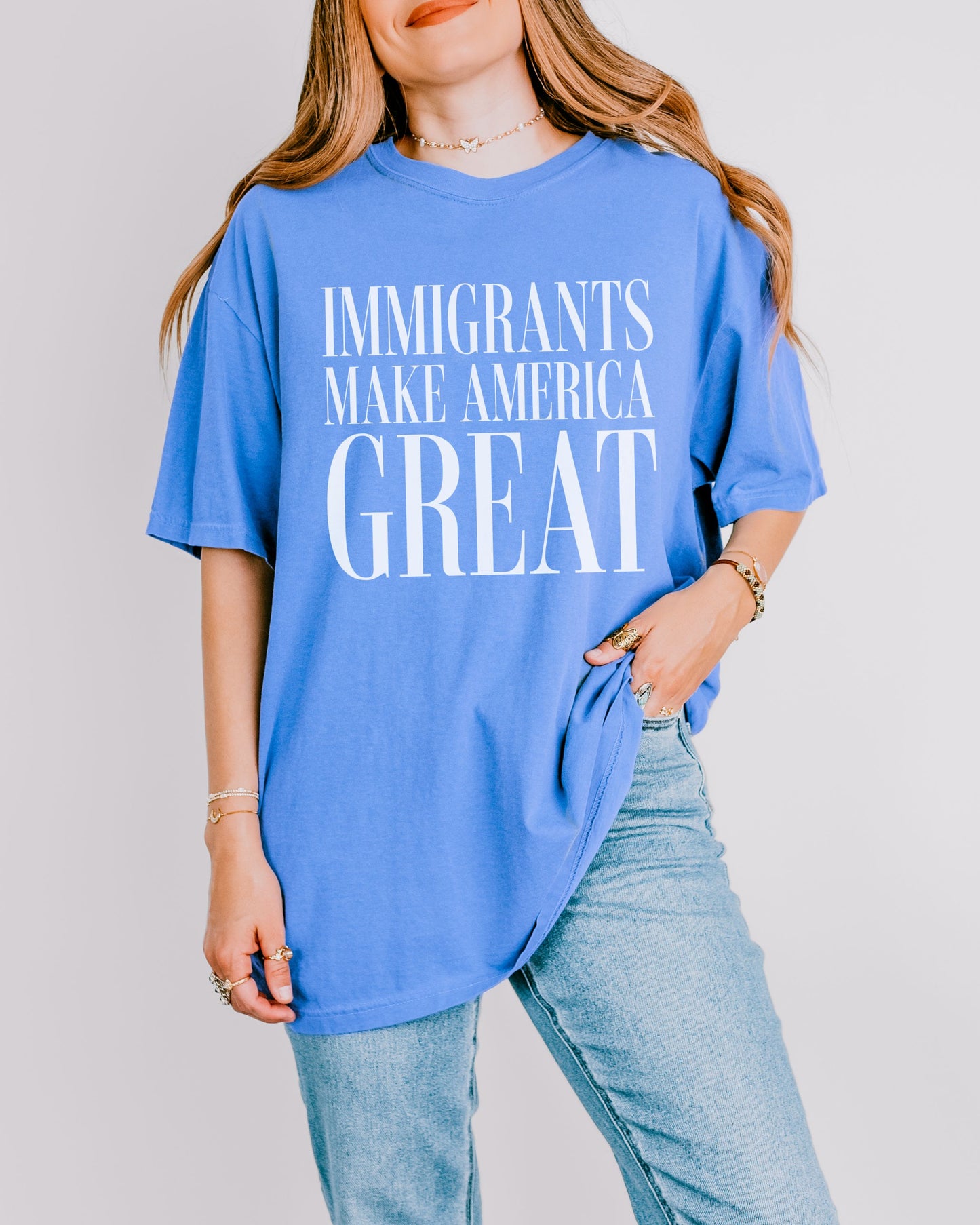 Person wearing a blue t-shirt with 'IMMIGRANTS MAKE AMERICA GREAT' text on a plain background