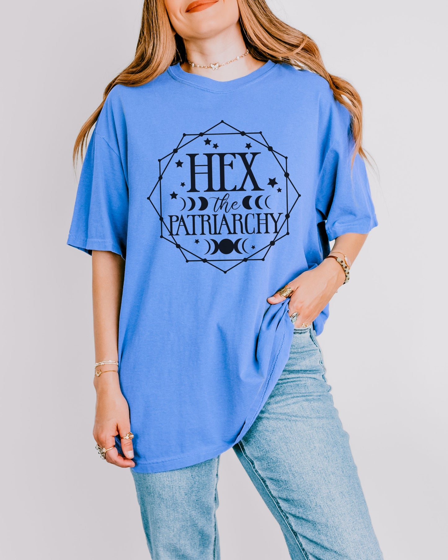 Person wearing a blue t-shirt with 'Hex the Patriarchy' text on a plain background