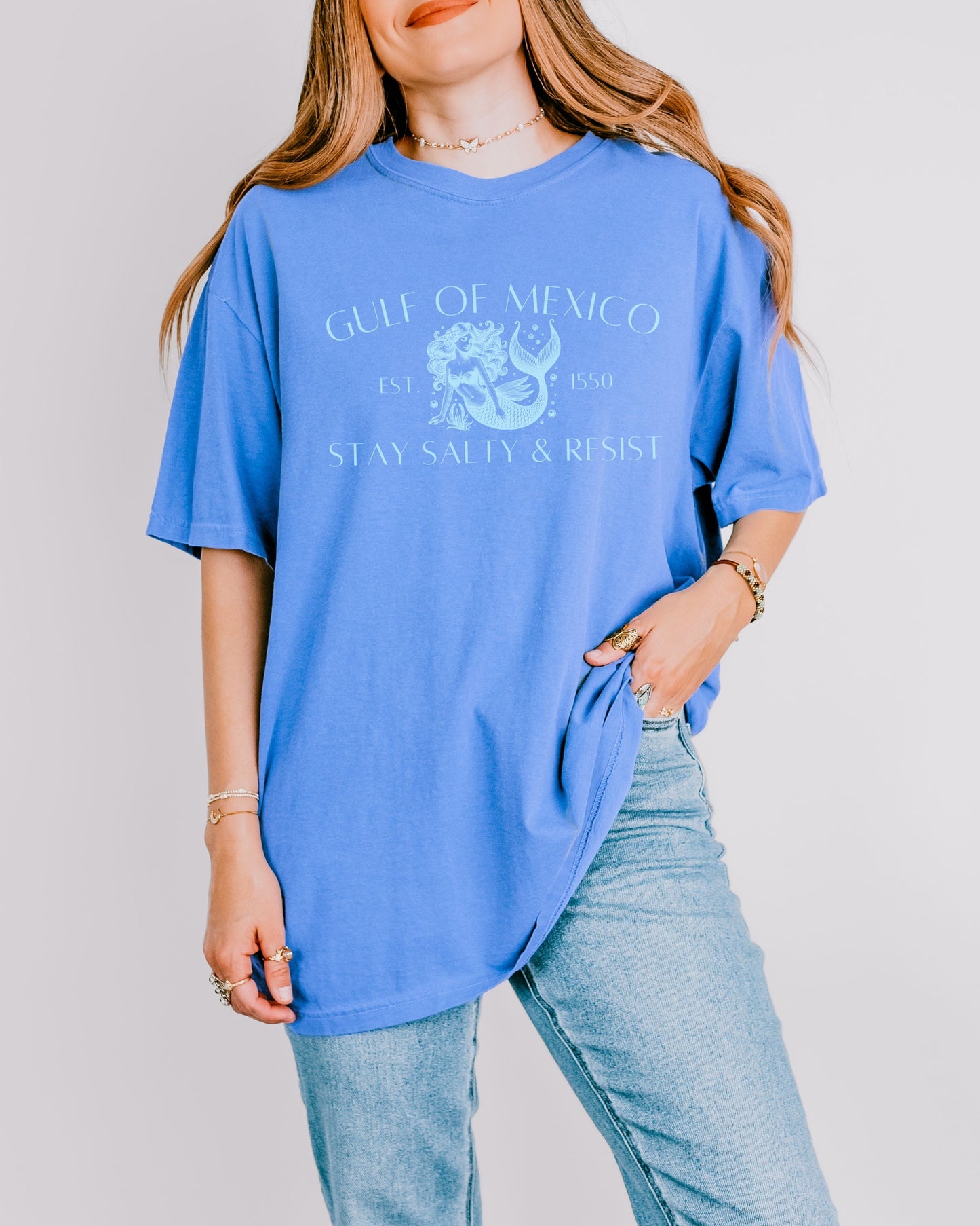 Person wearing a blue t-shirt with graphic design and text on a plain background