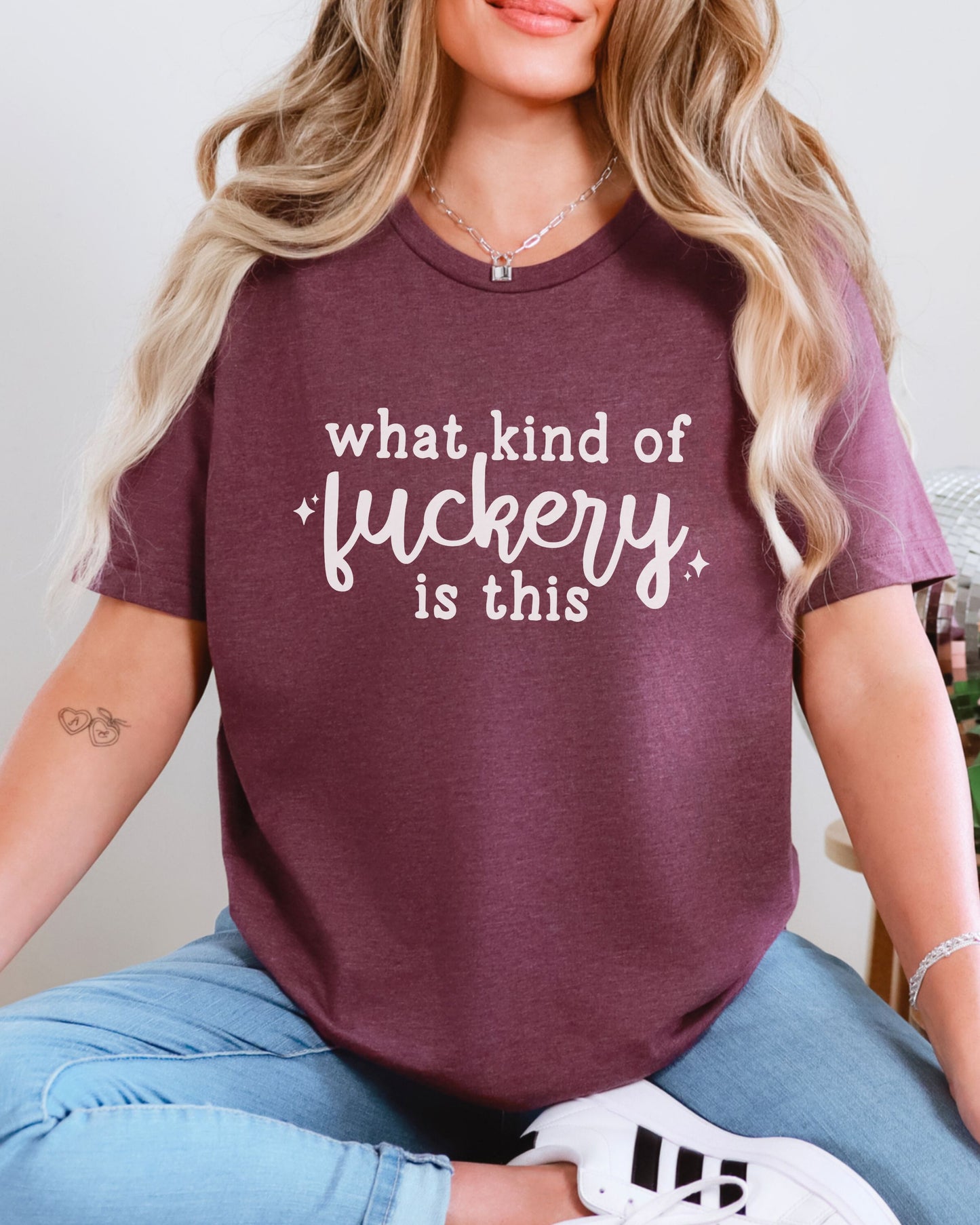Person wearing a maroon t-shirt with white text sitting on a chair.