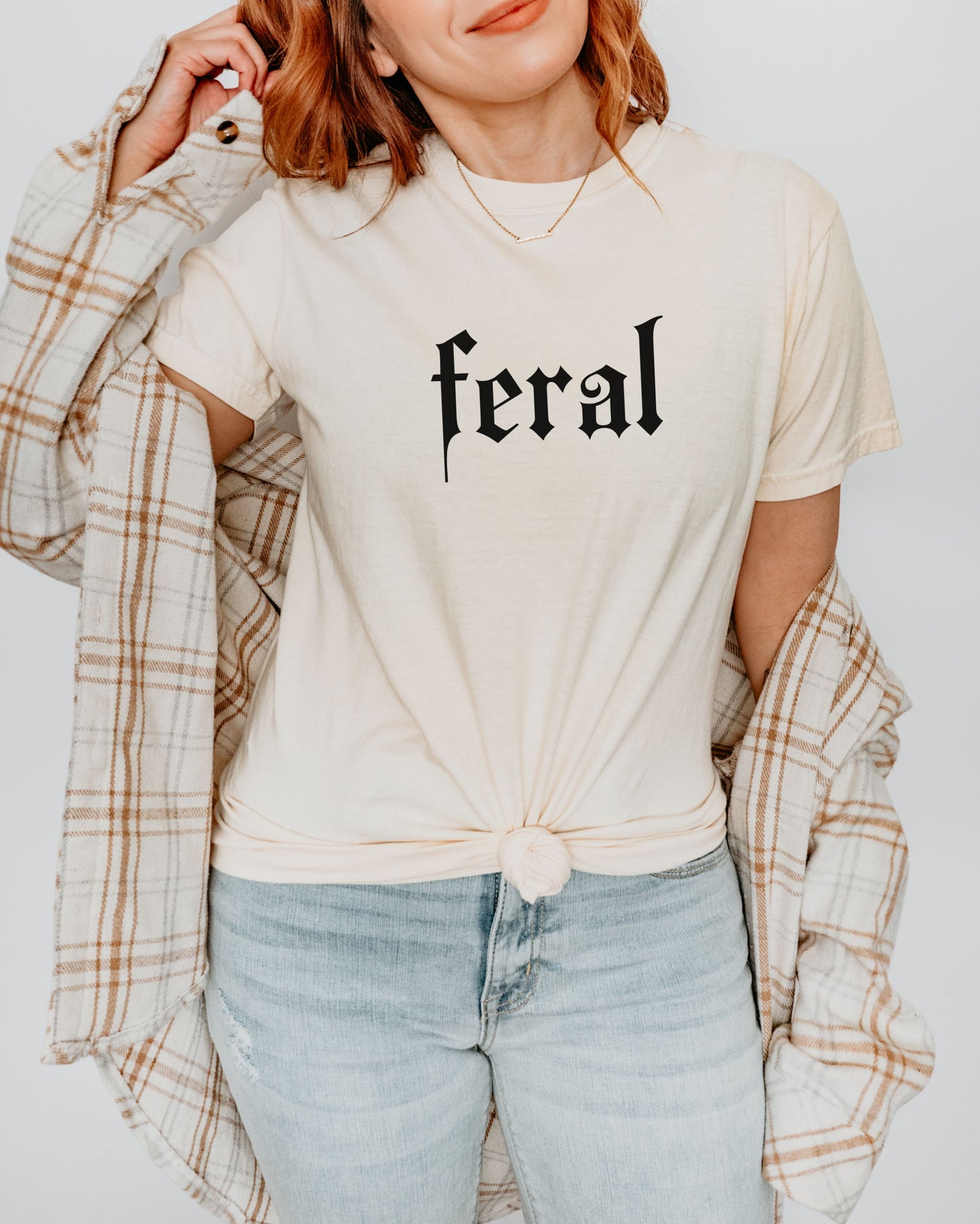 grunge aesthetic feral t-shirt in black font worn by model, in color ivory