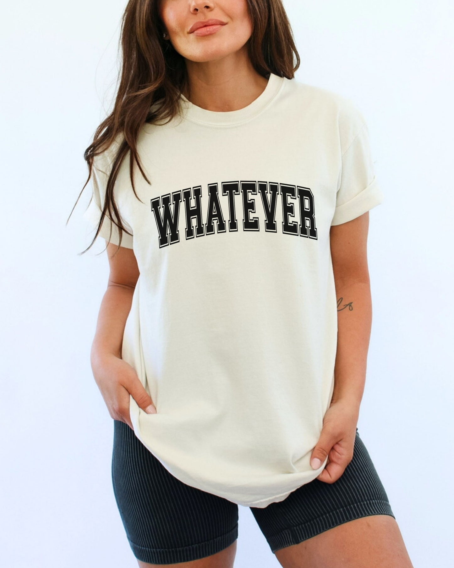 Woman wearing a white t-shirt with 'WHATEVER' text on a plain background