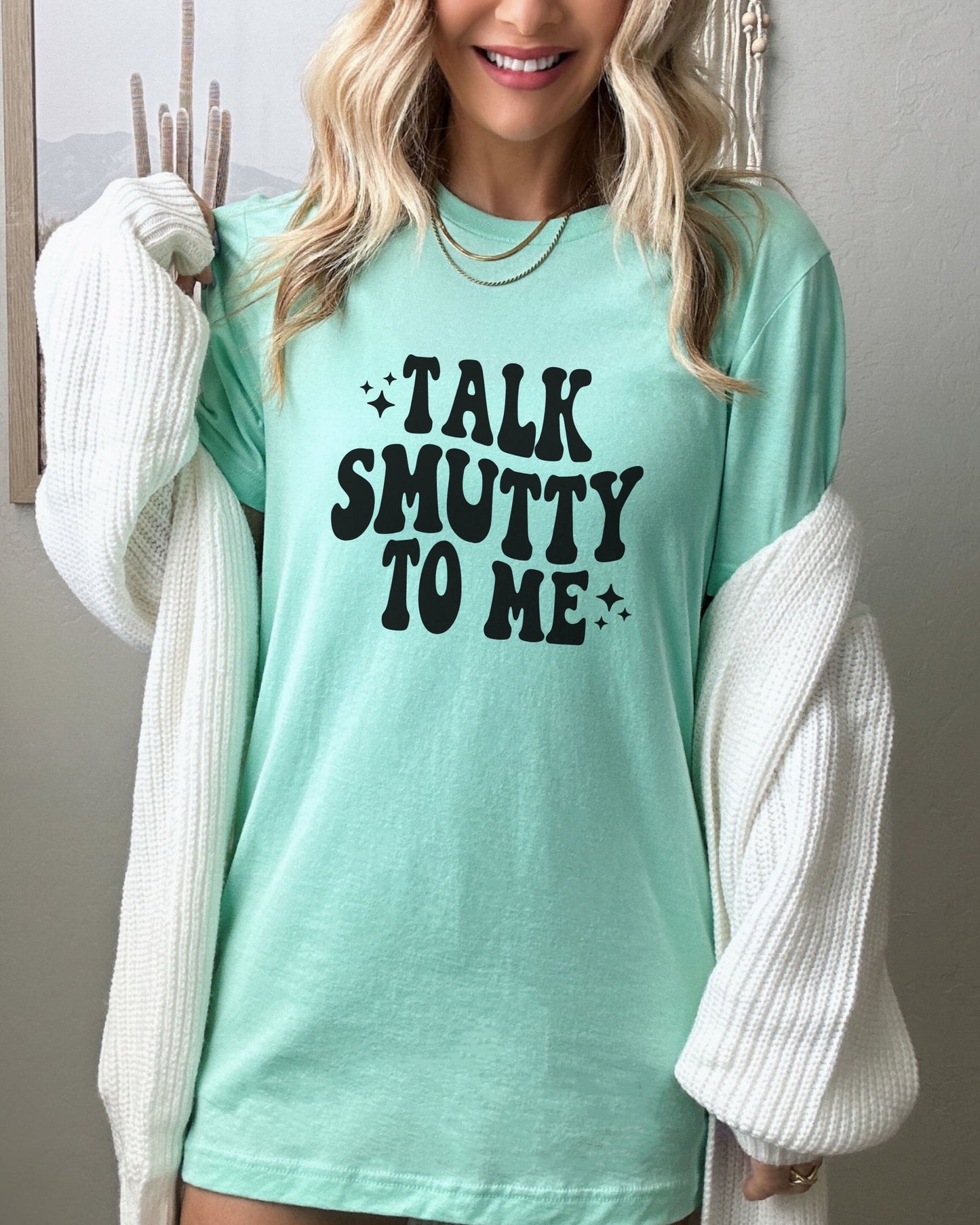 Person wearing a mint t-shirt with 'Talk Smutty To Me' text, standing against a neutral background.