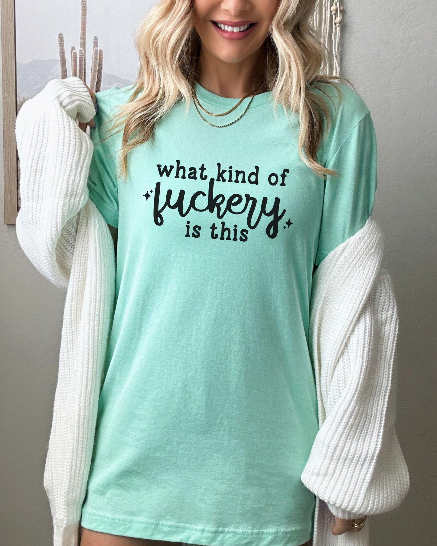 Person wearing a light blue t-shirt with text, standing against a neutral background