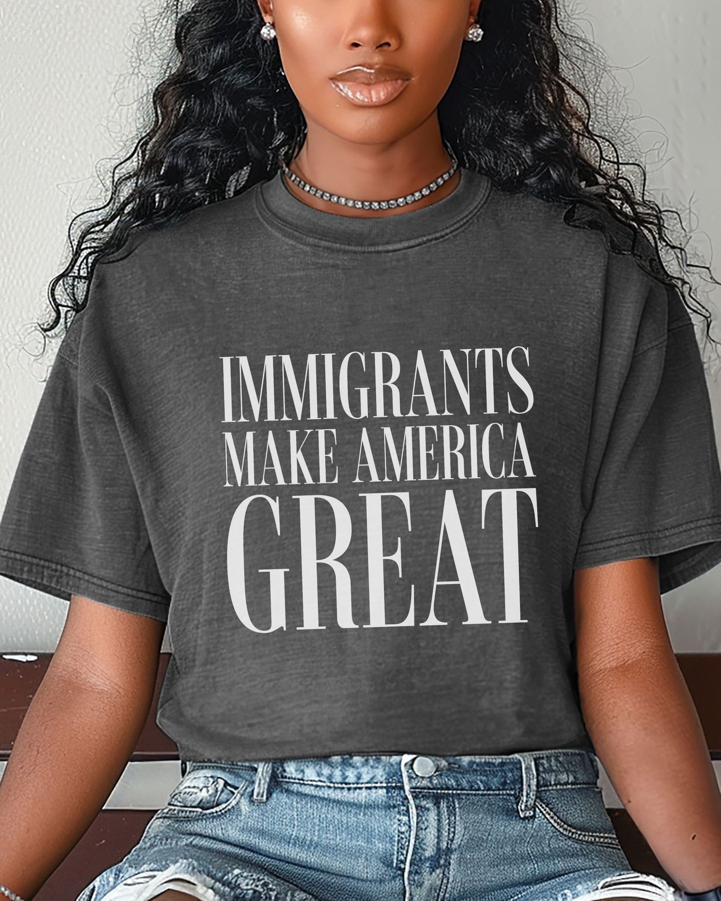 Person wearing a dark gray t-shirt with 'IMMIGRANTS MAKE AMERICA GREAT' text.