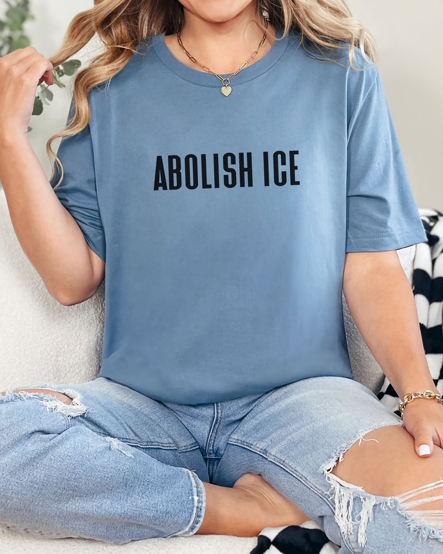 Person wearing a blue t-shirt with 'ABOLISH ICE' text.