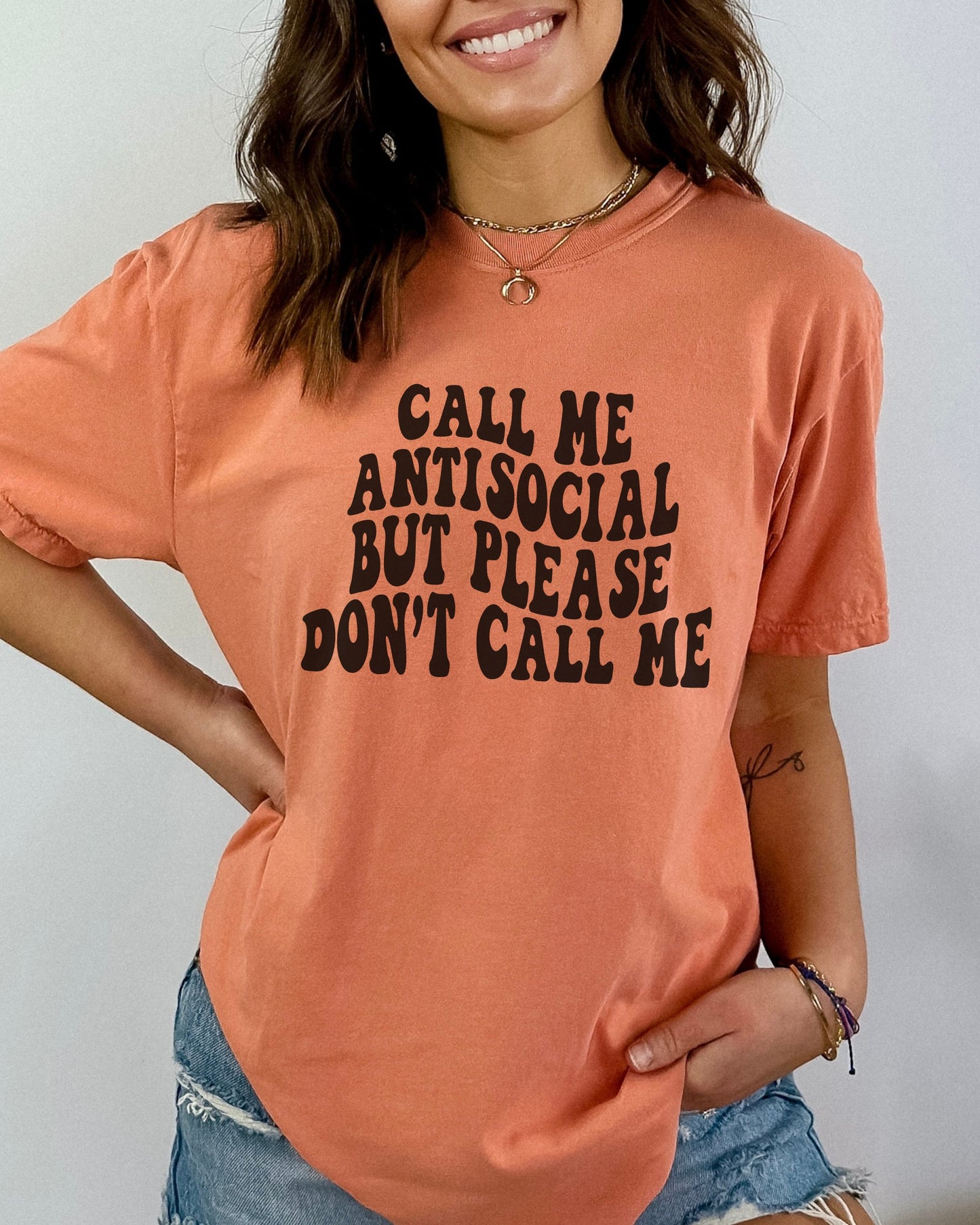 Person wearing a peach-colored t-shirt with text, standing against a plain background