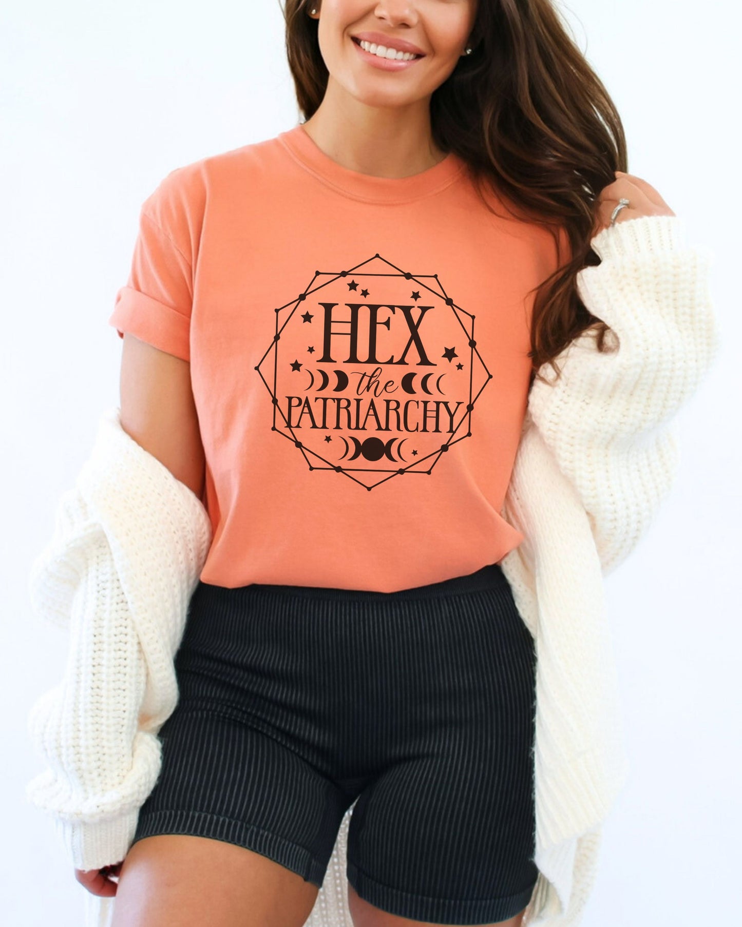Woman wearing an orange t-shirt with 'Hex the Patriarchy' text and design.