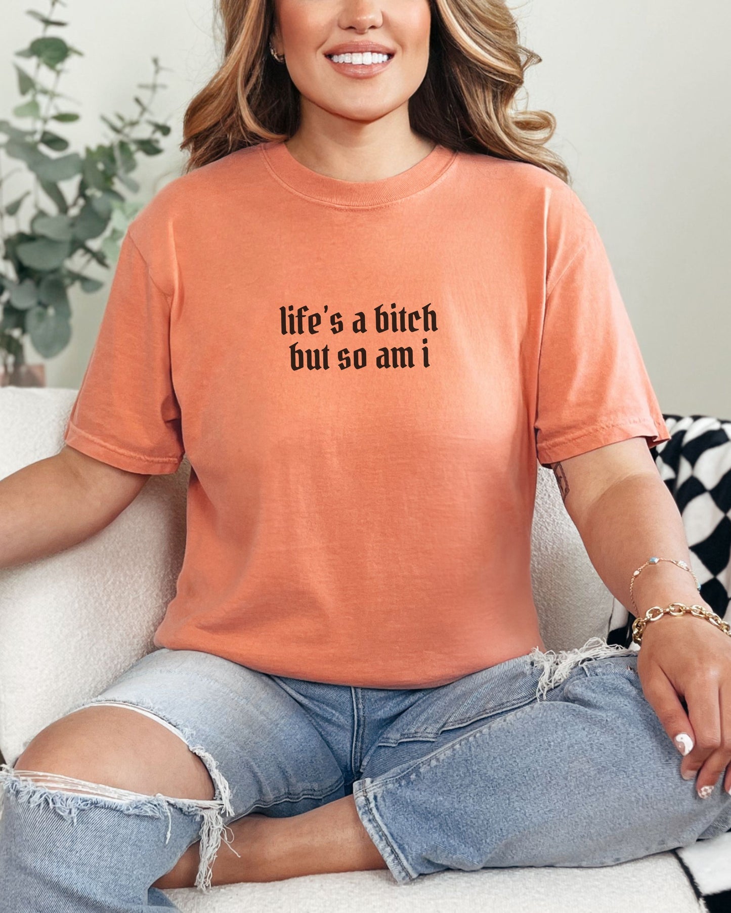 Person wearing an orange t-shirt with text, sitting on a couch.