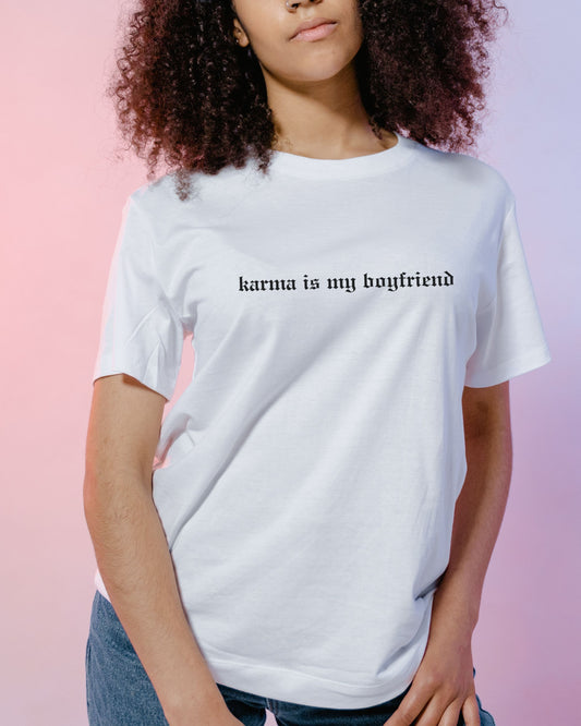 Person wearing a white t-shirt with 'karma is my boyfriend' text on a pink background