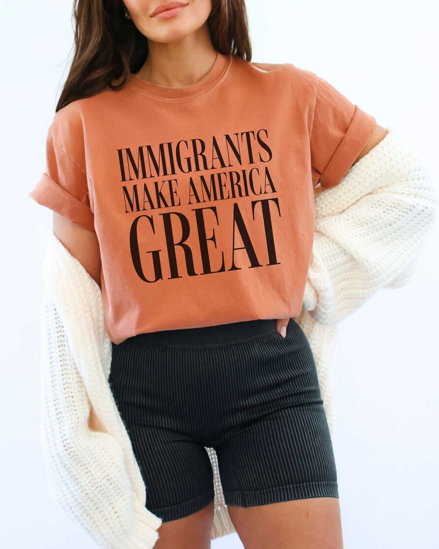 Person wearing a t-shirt with 'IMMIGRANTS MAKE AMERICA GREAT' text on a white background