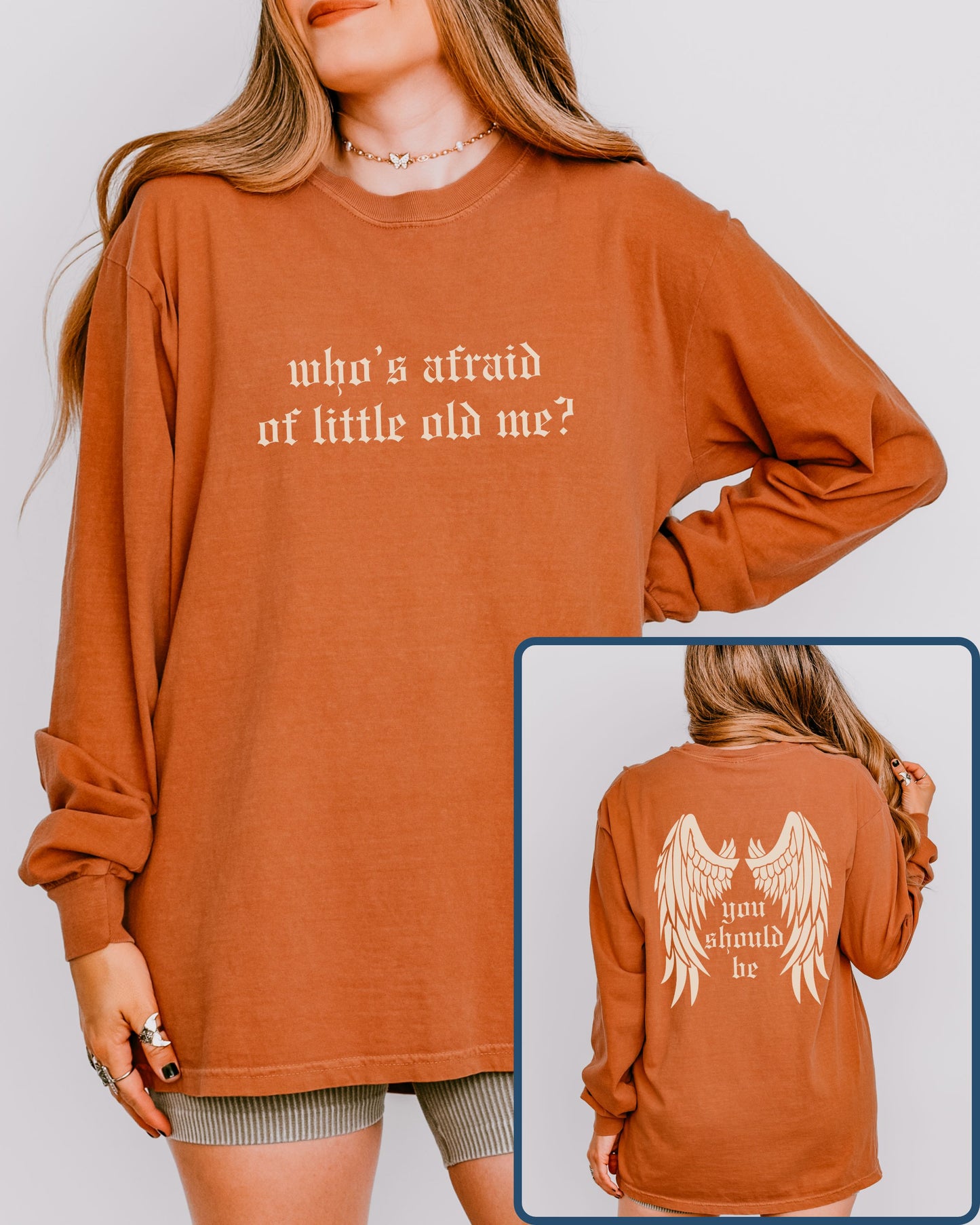 Person wearing a rust-colored sweatshirt with text on the front and back, on a plain background.