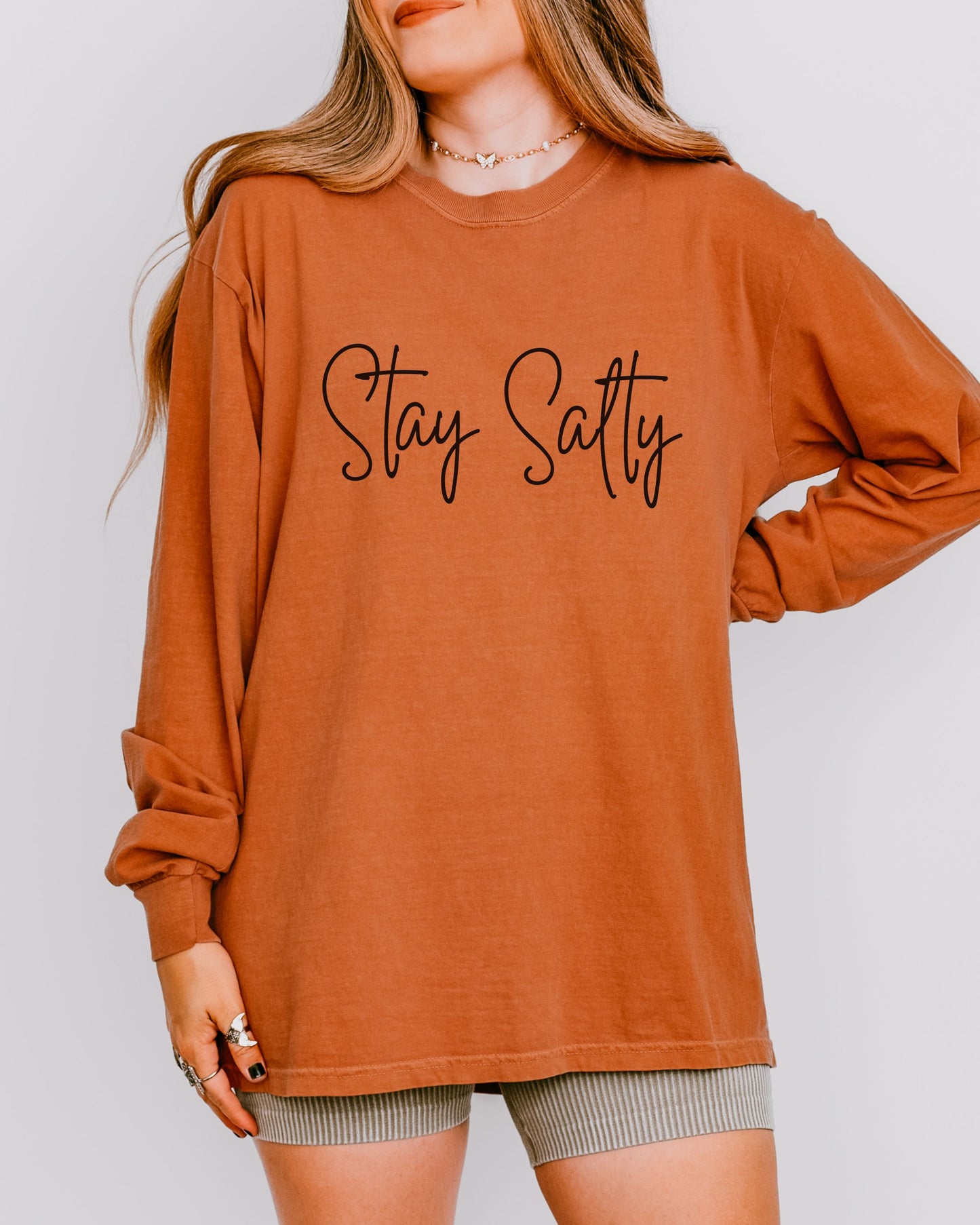 Person wearing a brown long-sleeve shirt with 'Stay Satty' text on a plain background