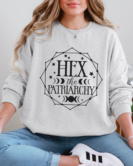 Person wearing a gray sweatshirt with 'Hex the Patriarchy' text design.