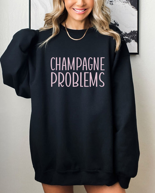 Person wearing a black sweatshirt with 'CHAMPAGNE PROBLEMS' text against a neutral background