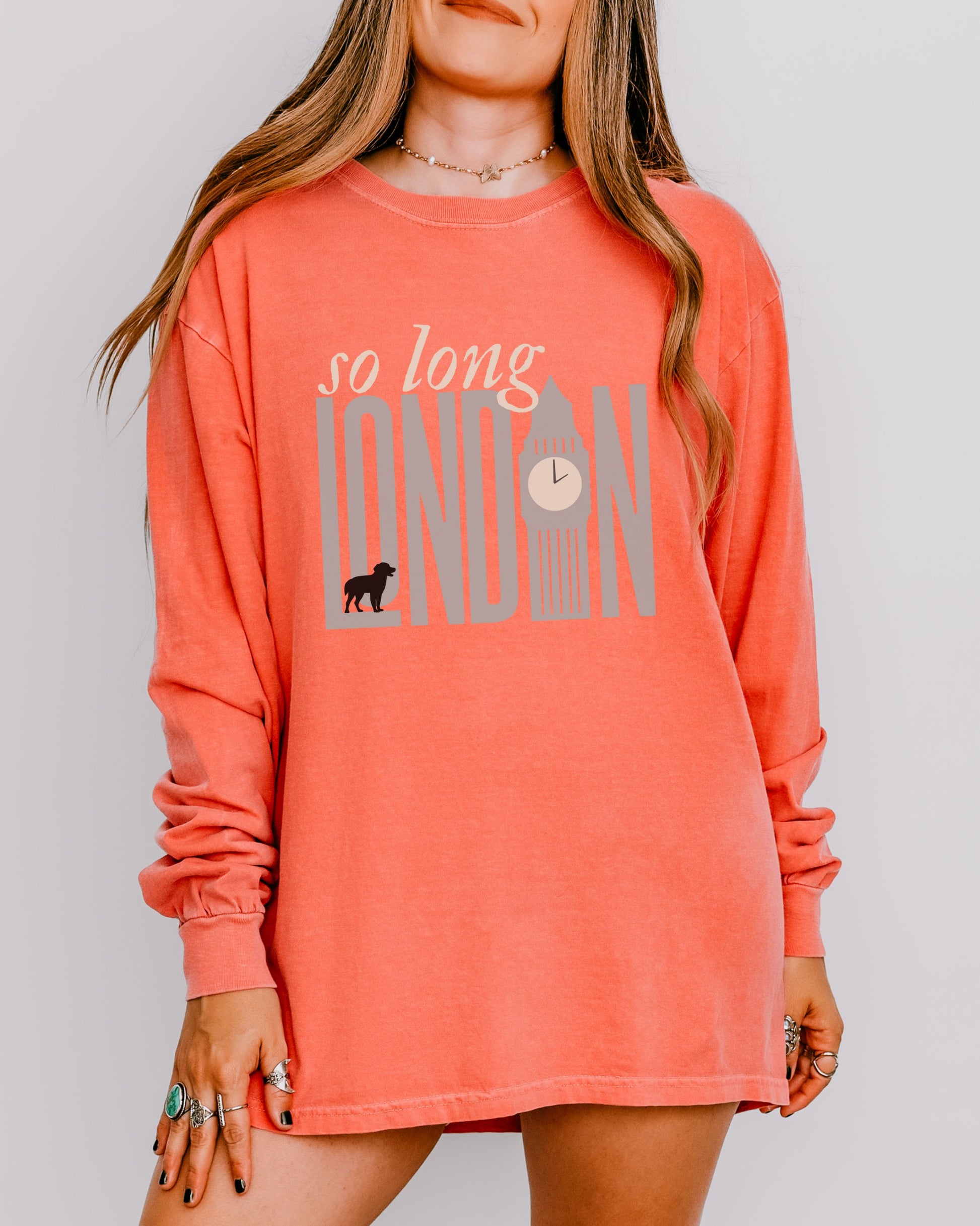 Person wearing a coral long-sleeve shirt with 'so long London' text and graphic.