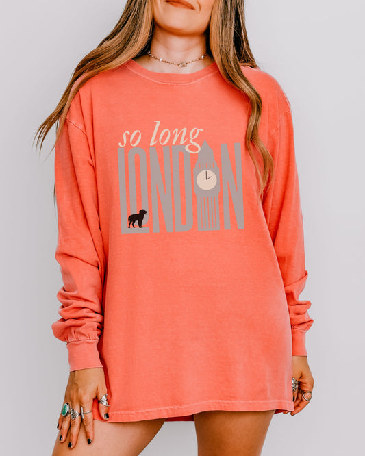 Person wearing a coral long-sleeve shirt with 'so long London' text and graphic.