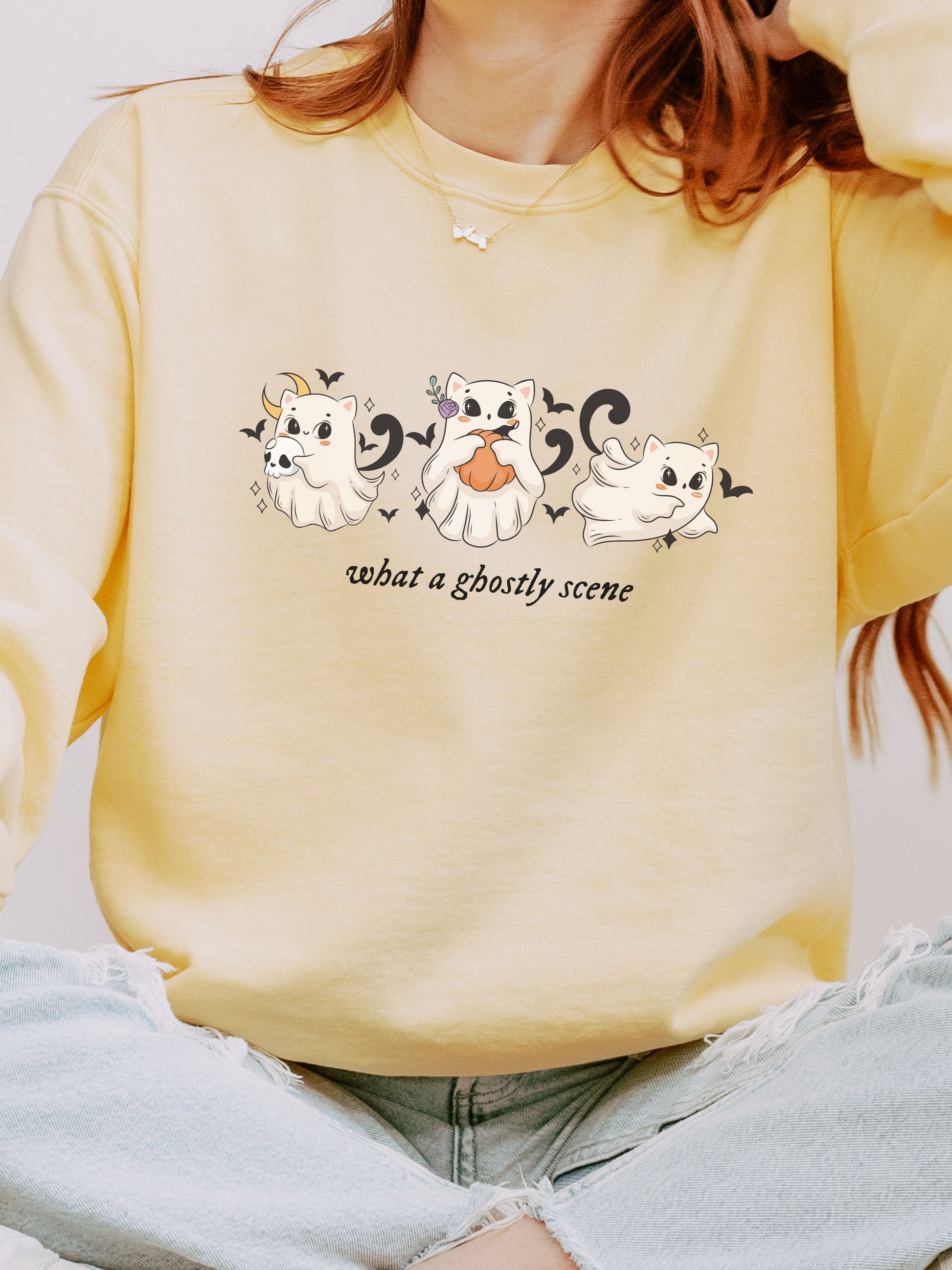 Person wearing a yellow sweatshirt with cartoon ghost designs and text.