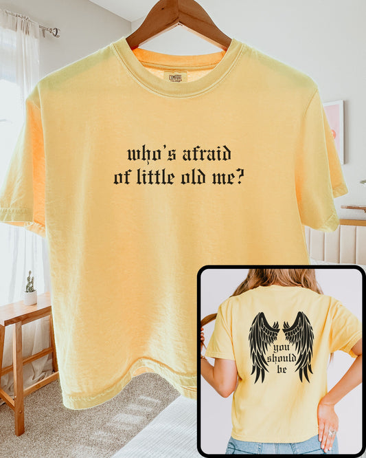 woman wearing comfort colors crop top in butter yellow with who’s afraid of little old me text on front and wings with you should be on back
