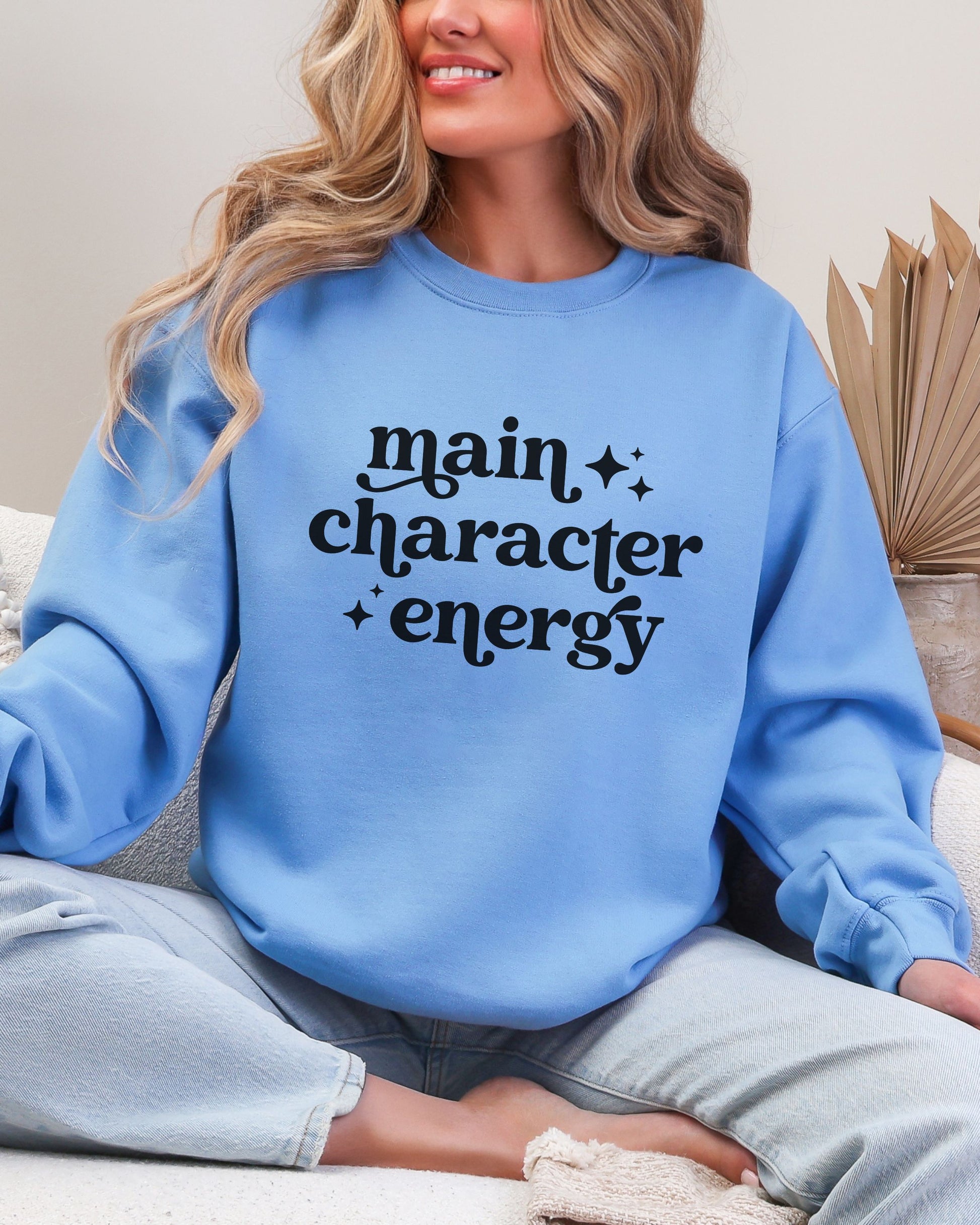 Person wearing a blue sweatshirt with 'main character energy' text.