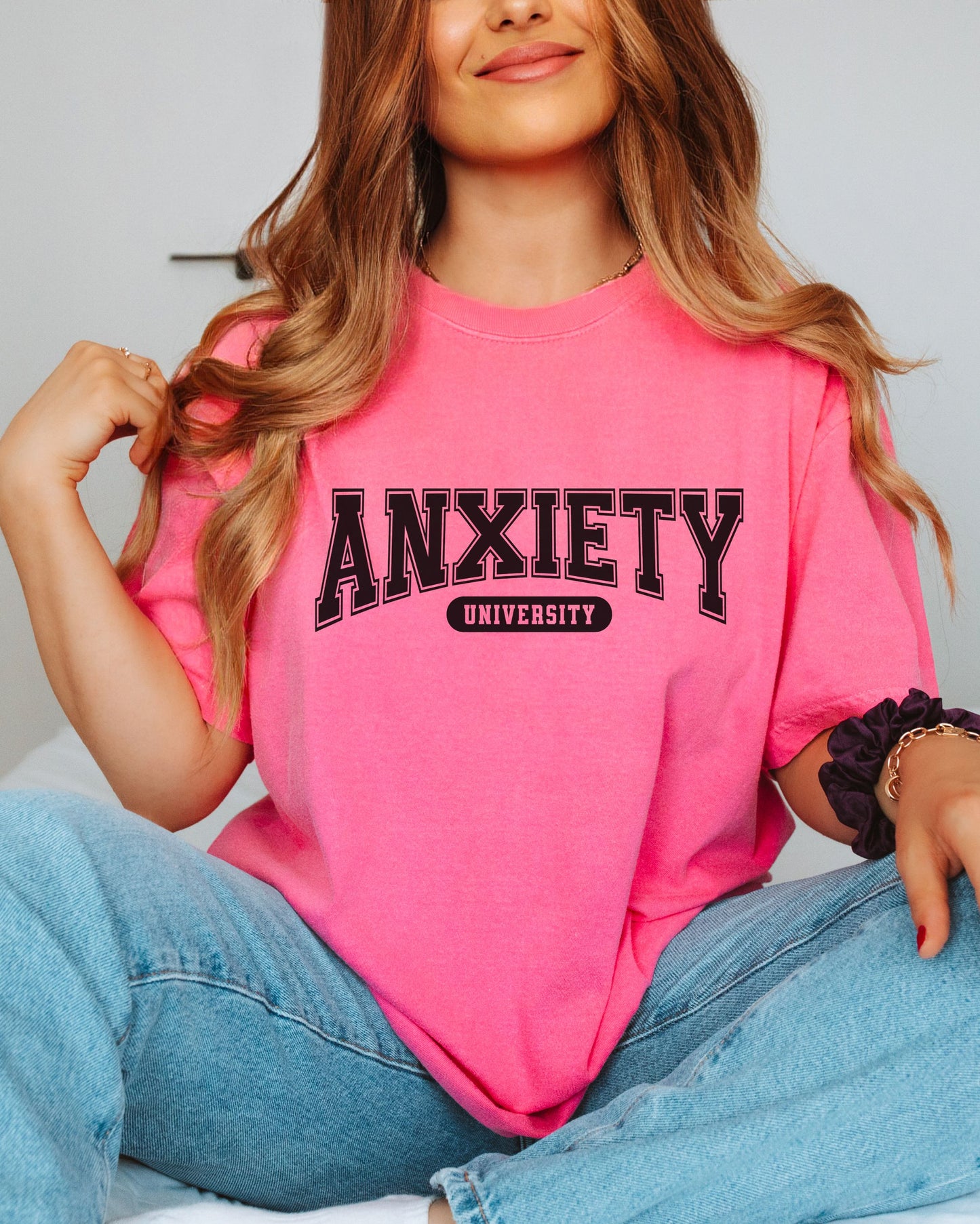 Person wearing a pink t-shirt with 'ANXIETY UNIVERSITY' text.