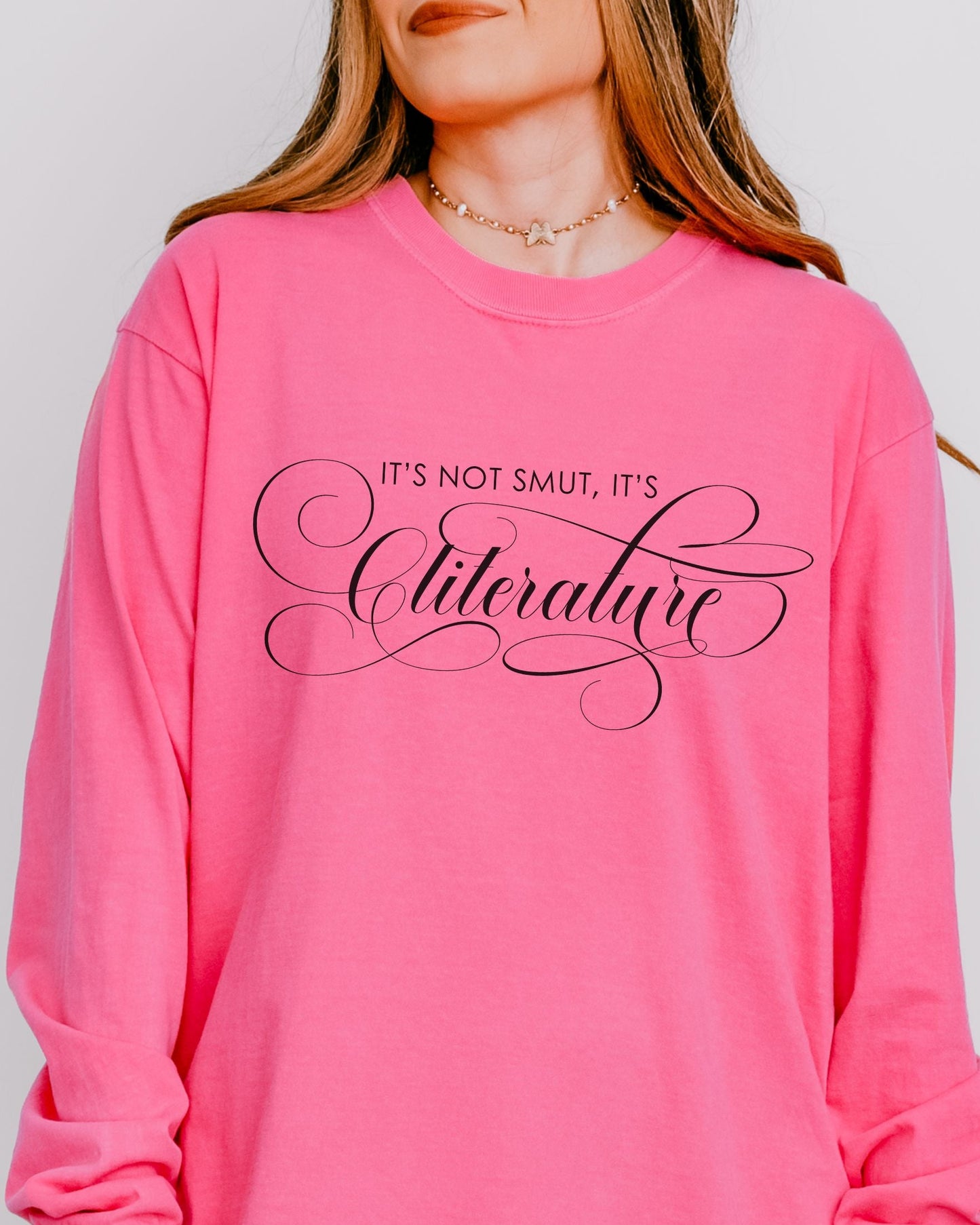 Person wearing a pink long-sleeve shirt with text on a plain background