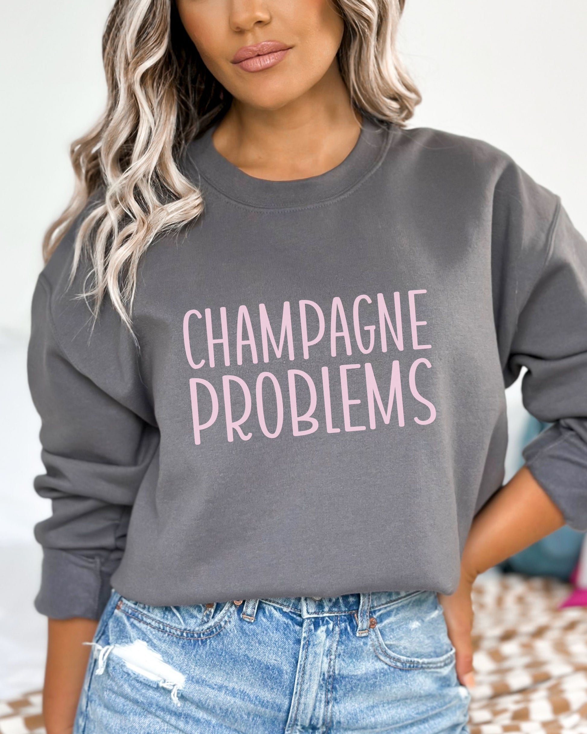 Person wearing a gray sweatshirt with 'CHAMPAGNE PROBLEMS' text in pink.