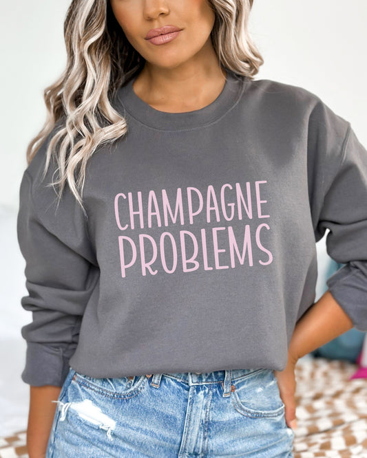 Person wearing a gray sweatshirt with 'CHAMPAGNE PROBLEMS' text in pink.