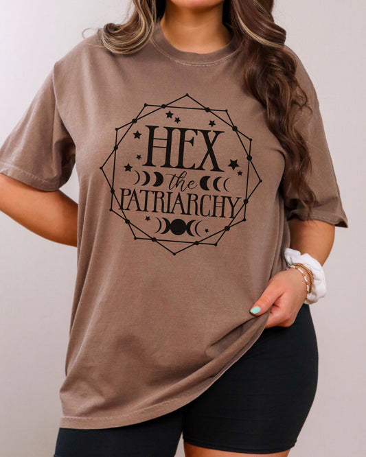 Person wearing a brown t-shirt with 'Hex the Patriarchy' text design.