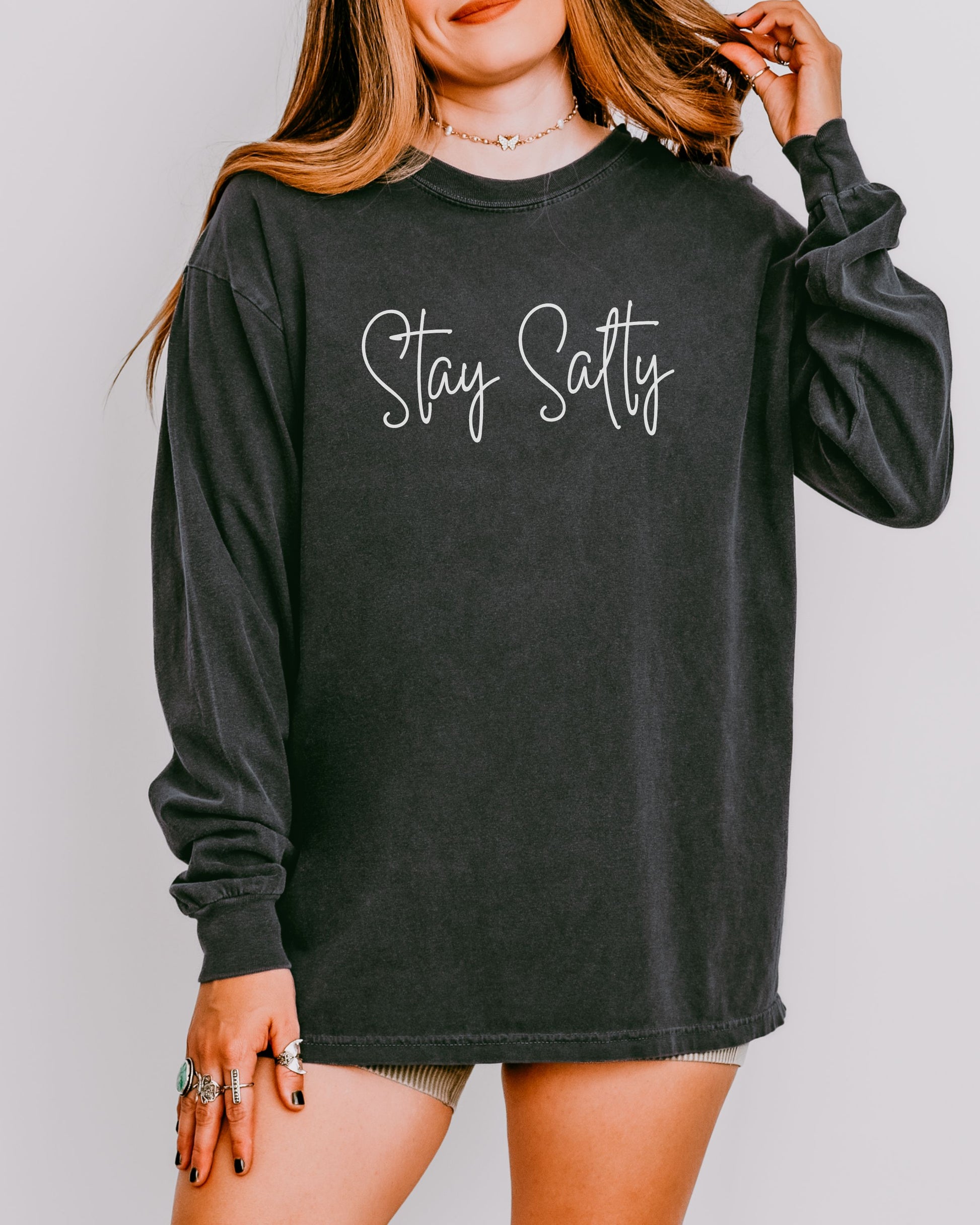 Person wearing a black long-sleeve shirt with 'Stay Satty' text on a plain background