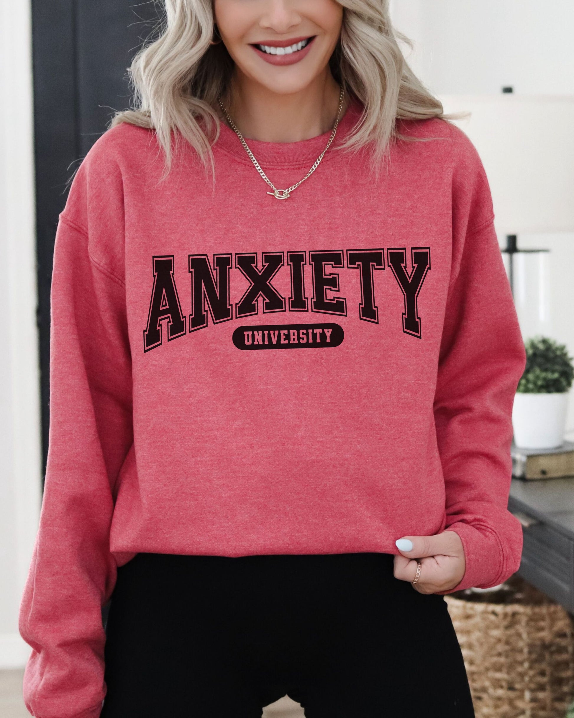 Person wearing a red sweatshirt with 'ANXIETY UNIVERSITY' text indoors.