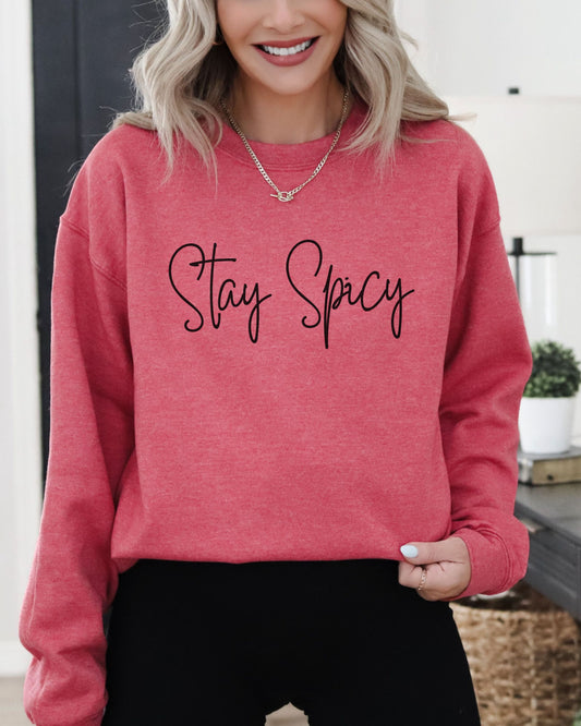 Person wearing a pink sweatshirt with 'Stay Spicy' text in a home setting
