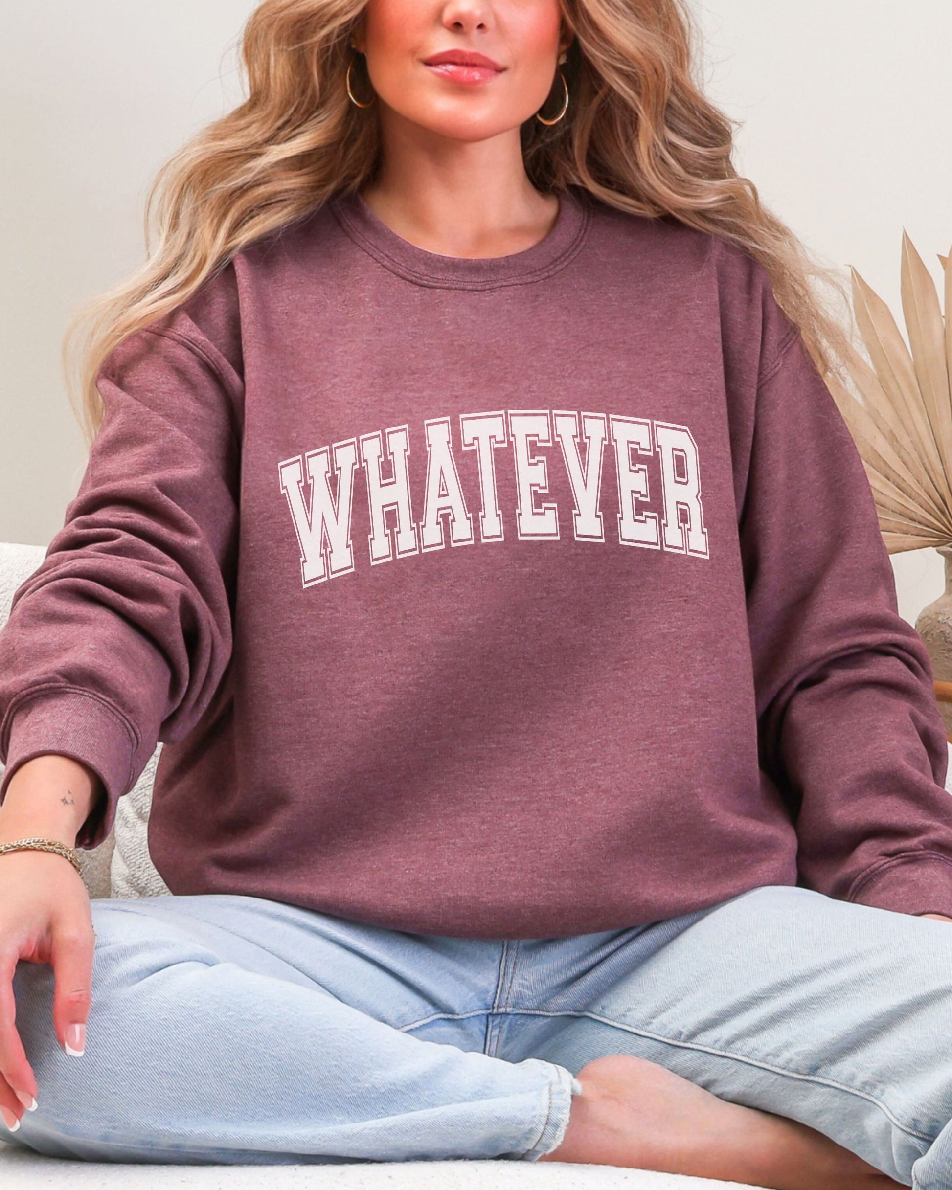 Person wearing a maroon sweatshirt with 'WHATEVER' text, sitting on a couch.