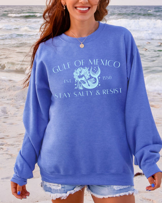 Woman wearing a blue sweatshirt with 'Gulf of Mexico' text on a beach