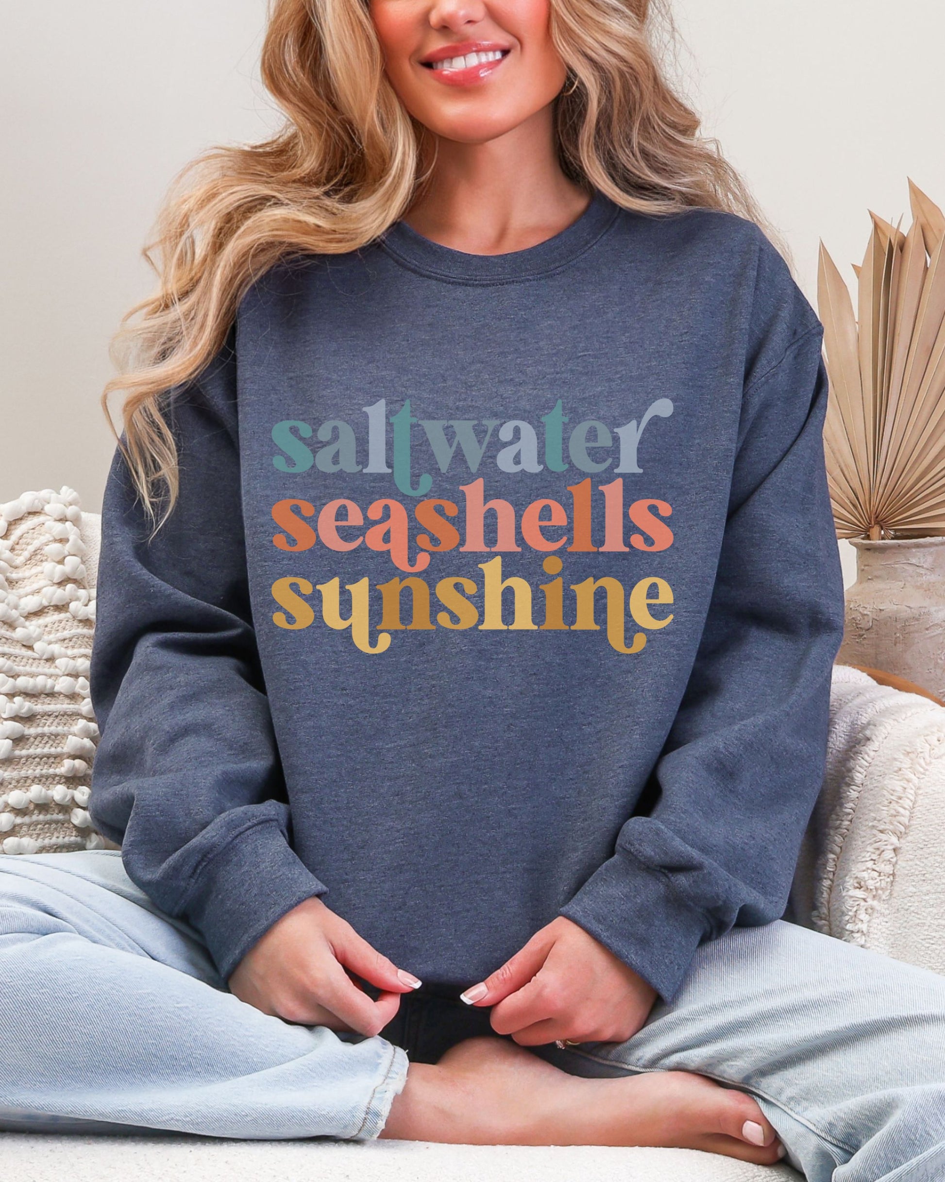 Person wearing a blue sweatshirt with 'saltwater seashells sunshine' text.