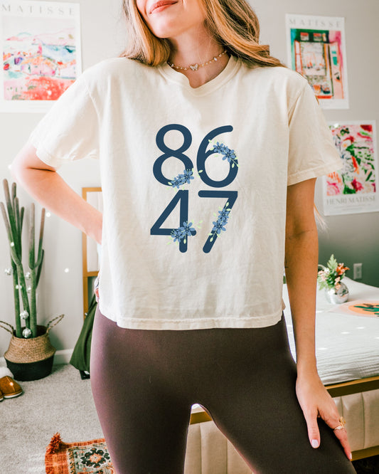 Person wearing a white t-shirt with blue numbers 8647 in a casual indoor setting