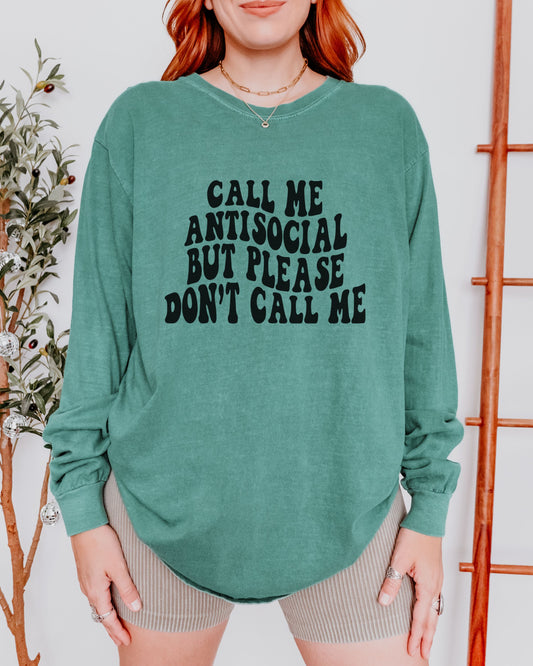 Person wearing a green sweatshirt with text, standing against a white wall with decorative elements.