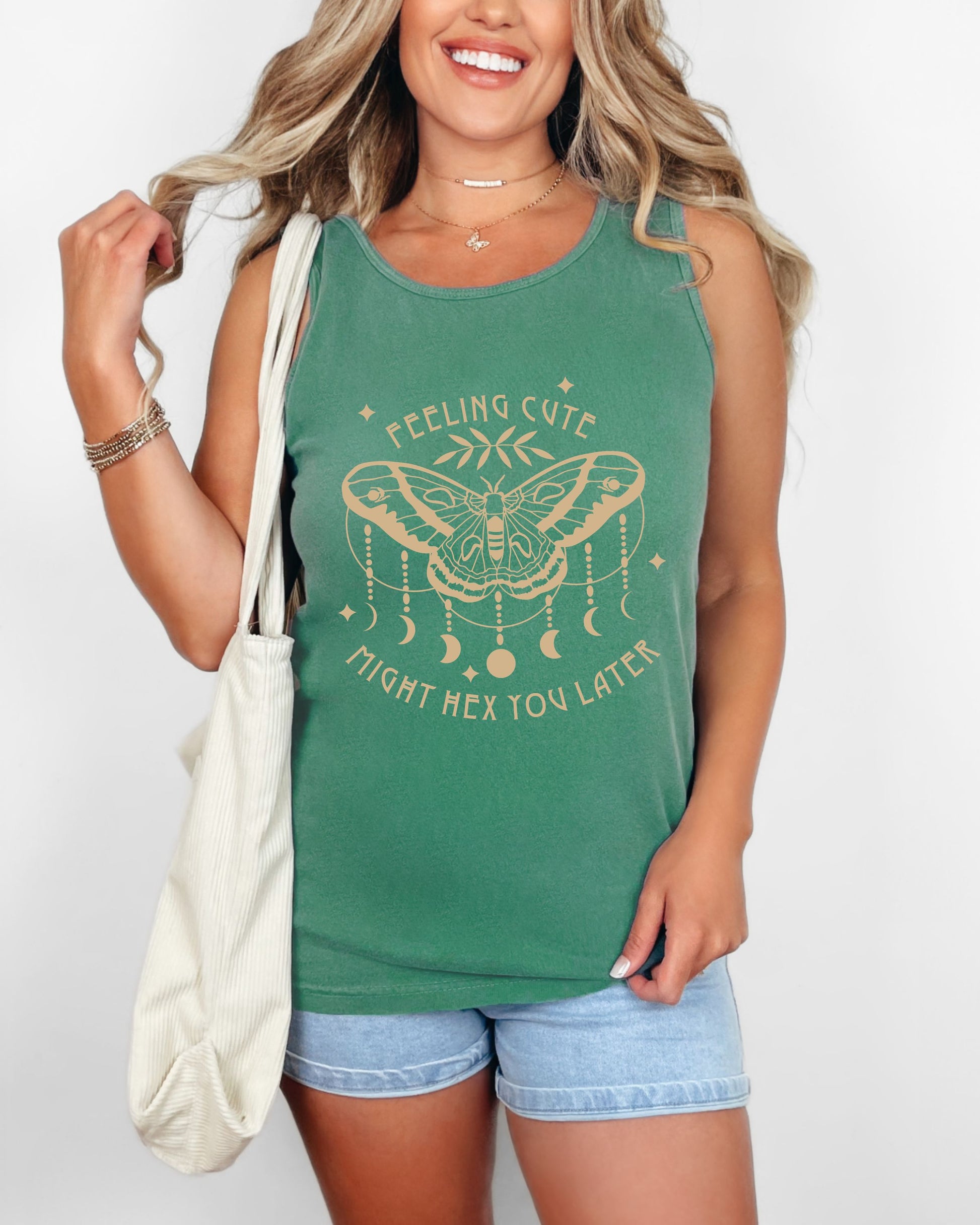 Woman wearing a green tank top with a butterfly design and text, holding a white bag.