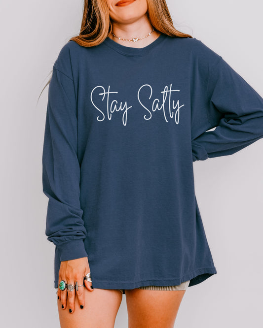 Person wearing a navy blue long-sleeve shirt with 'Stay Sassy' text on a plain background