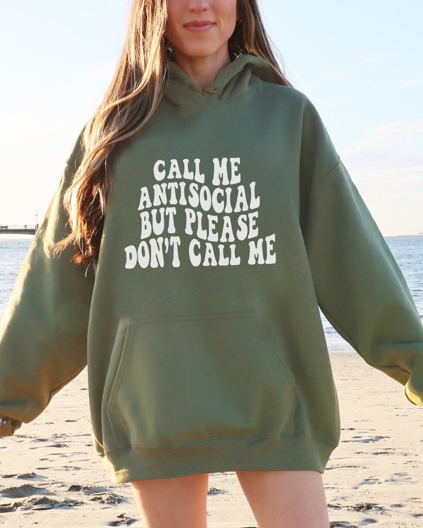 Person wearing a green hoodie with text on a beach